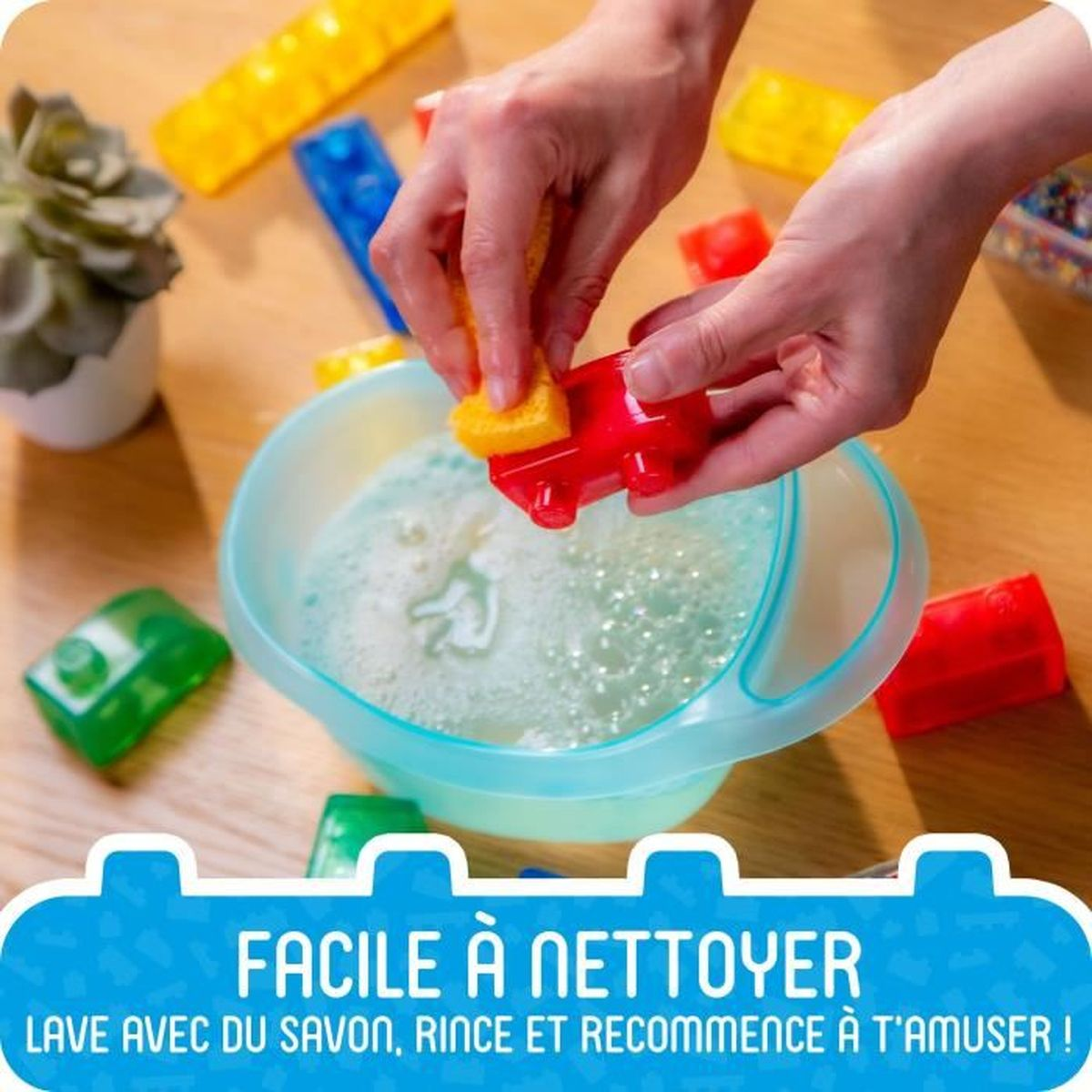 Hände reinigen ein rotes Spielzeugauto mit einem gelben Schwamm in einer Schüssel mit Seifenwasser.