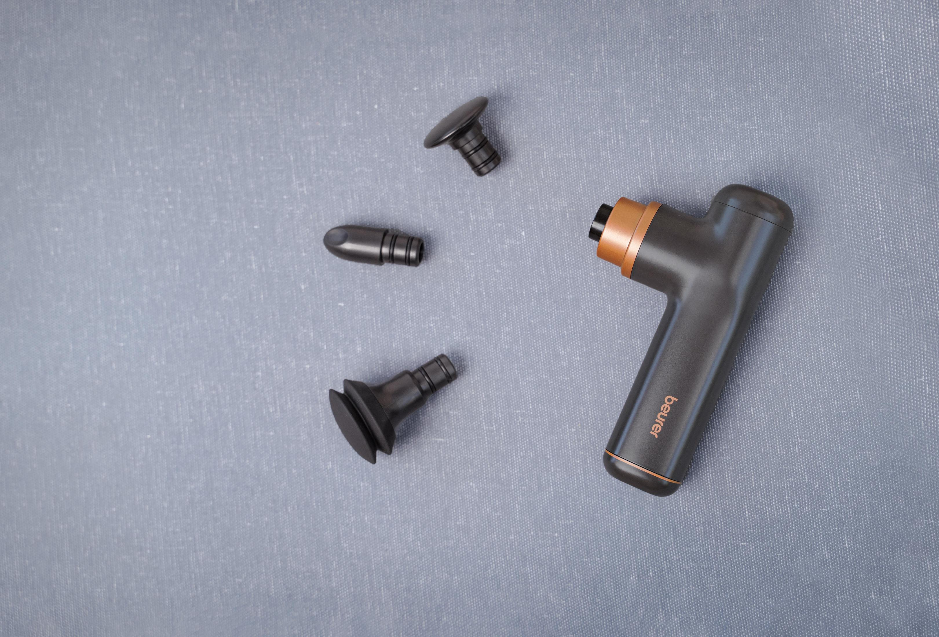 Una pistola massaggiante nera con tre accessori su tessuto grigio.