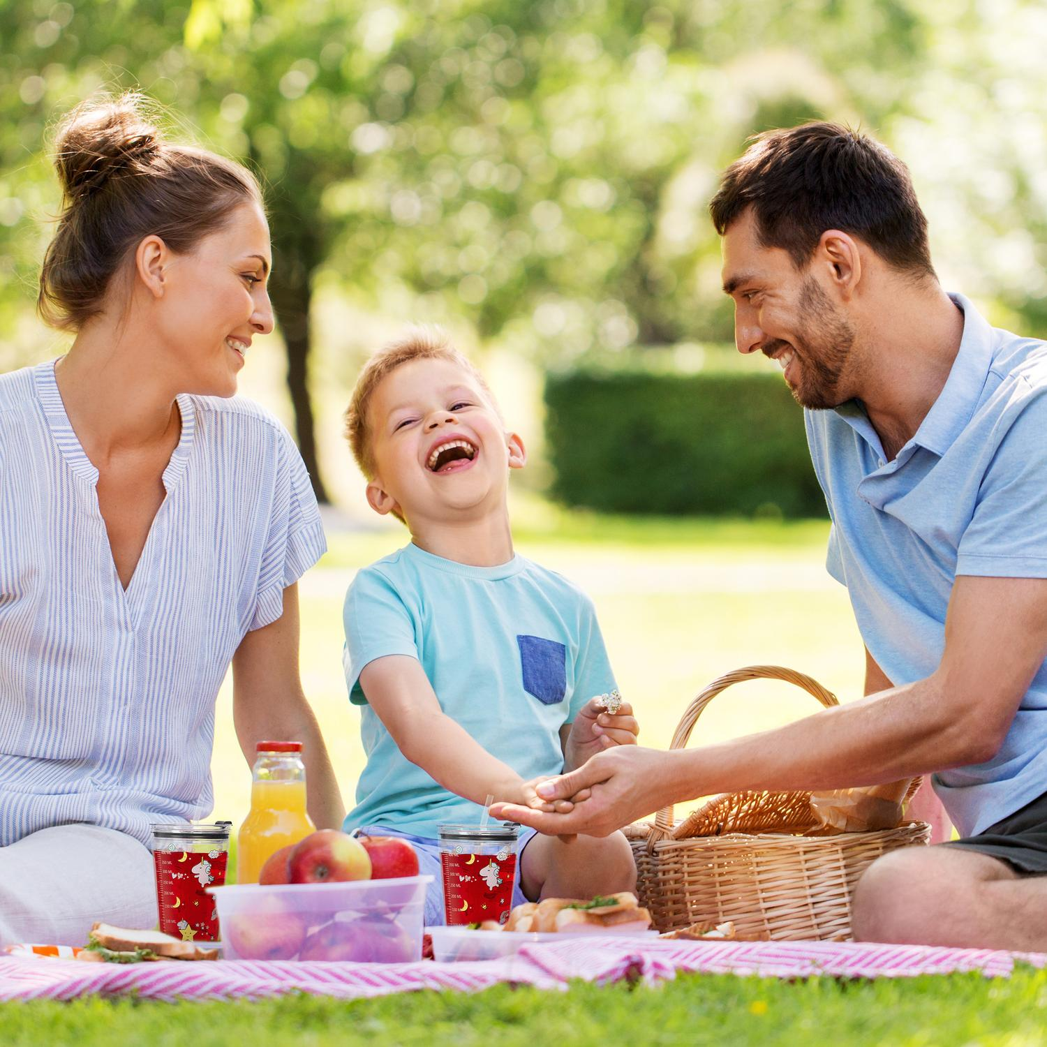 Una familia disfruta de un picnic en el parque con comida y bebidas.