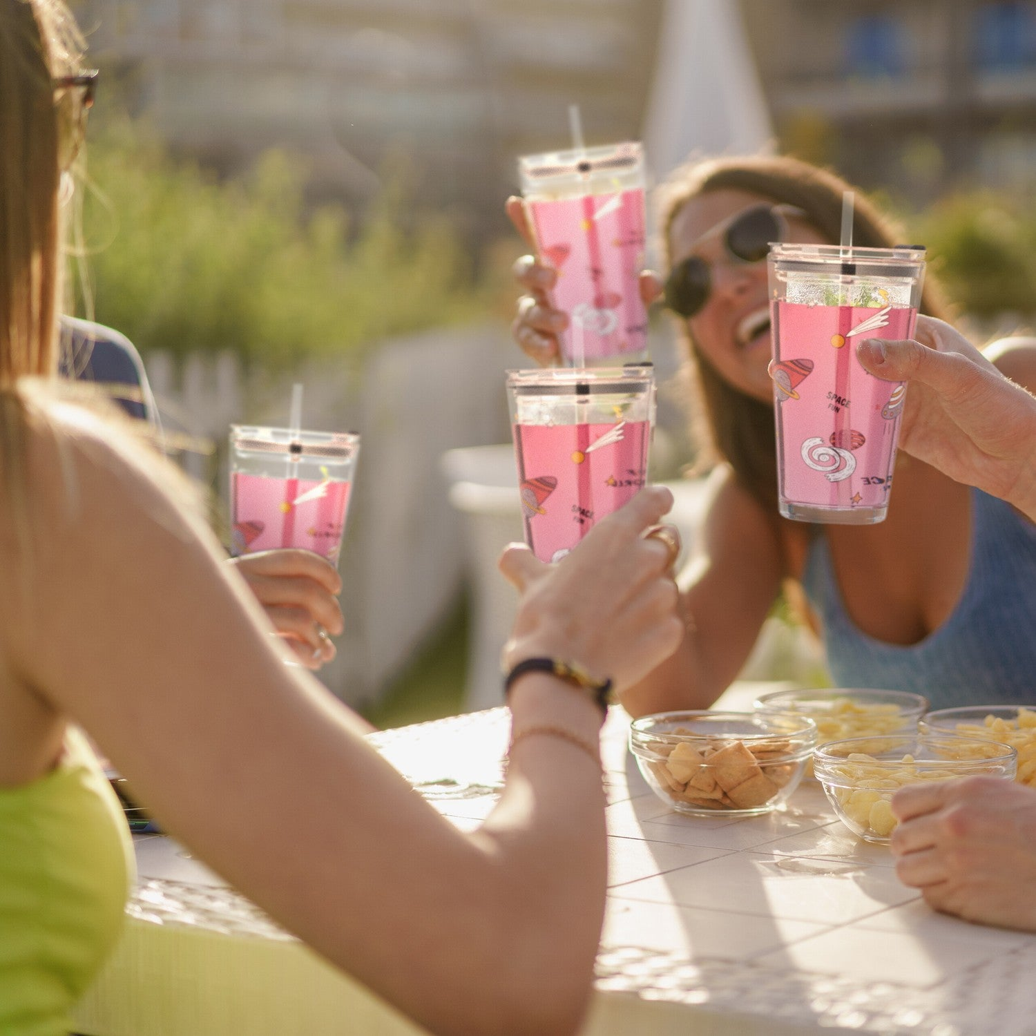 Amigos brindan con bebidas rosas con diseños espaciales al aire libre.