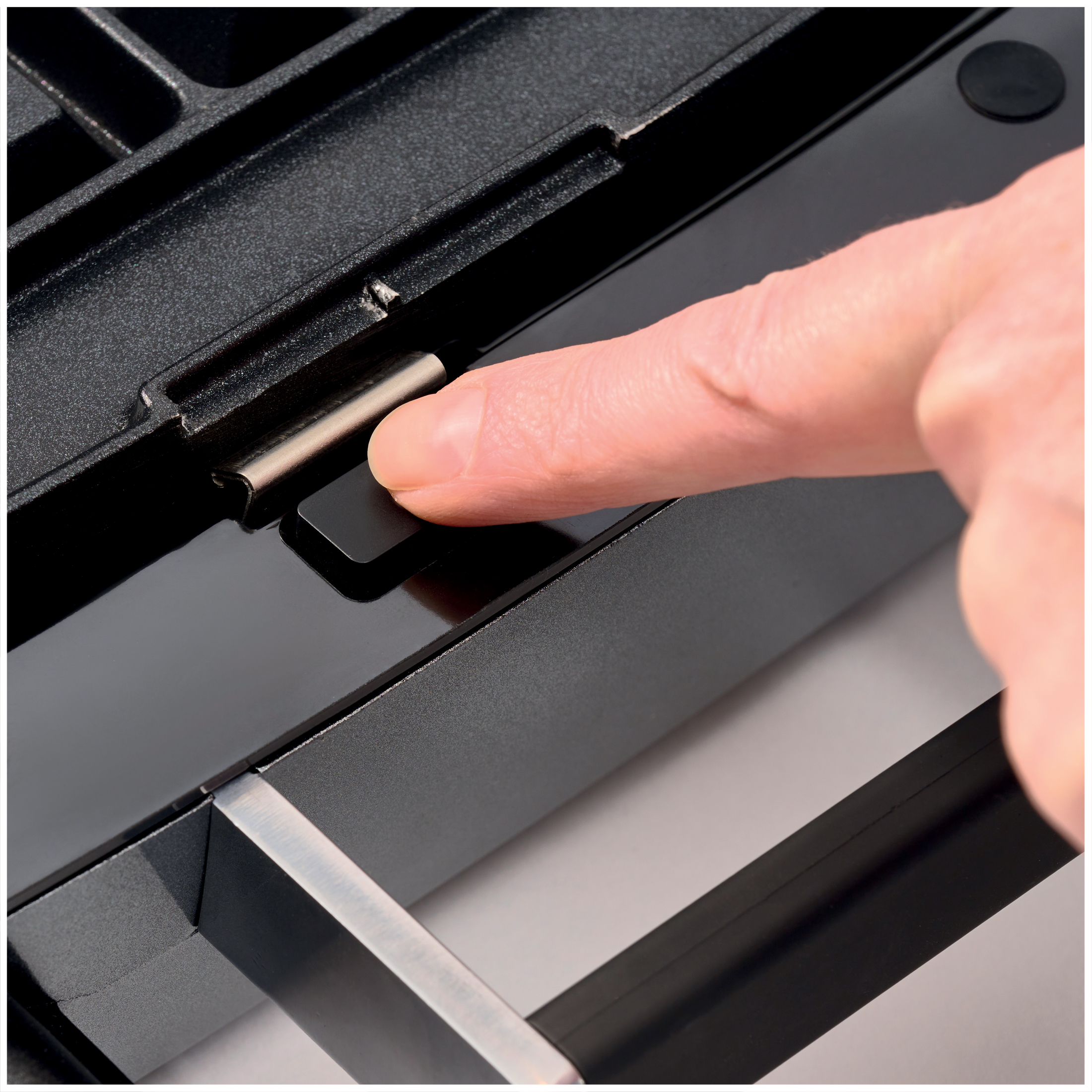A finger presses a black button on a black device.