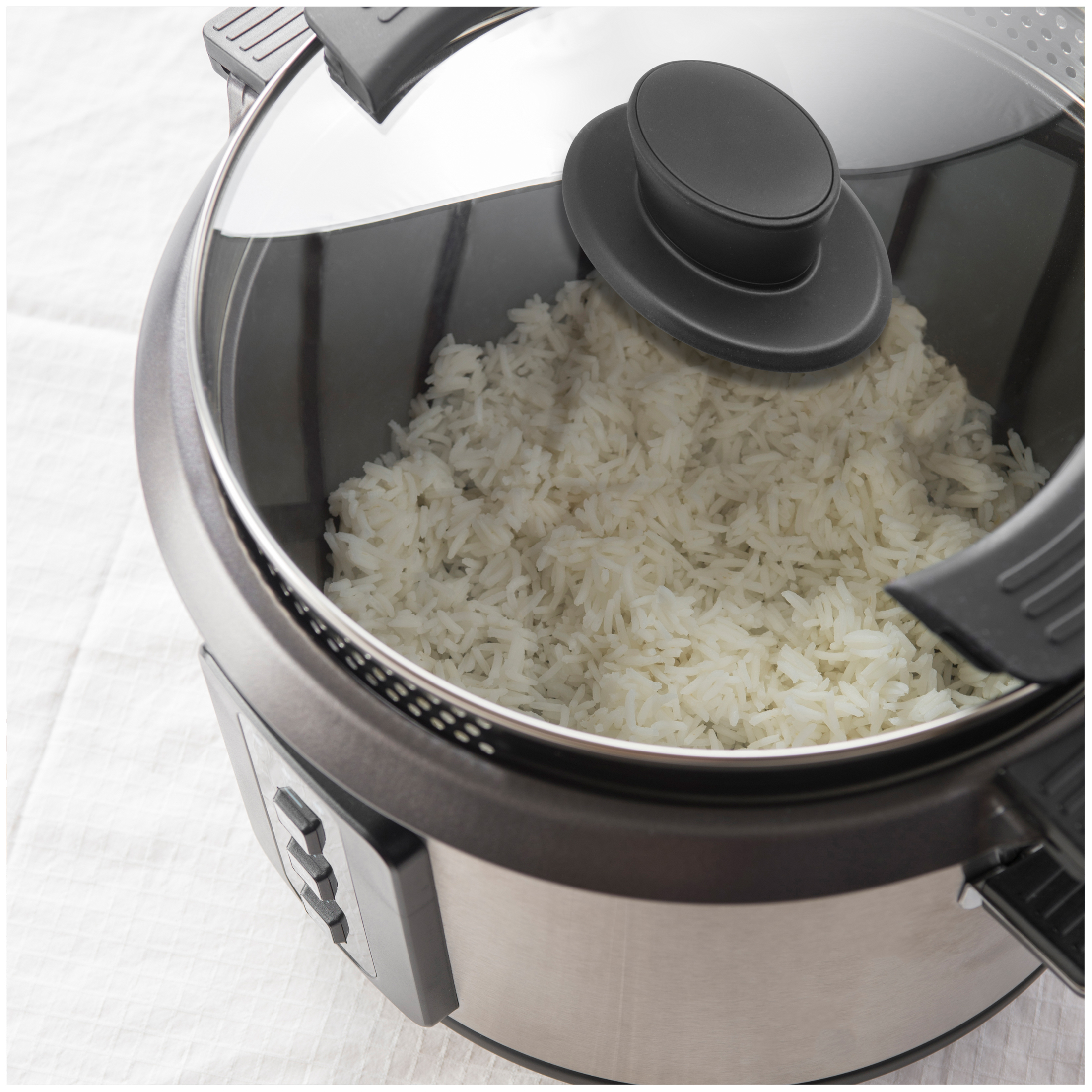 A rice cooker filled with freshly cooked rice, featuring a glass lid.