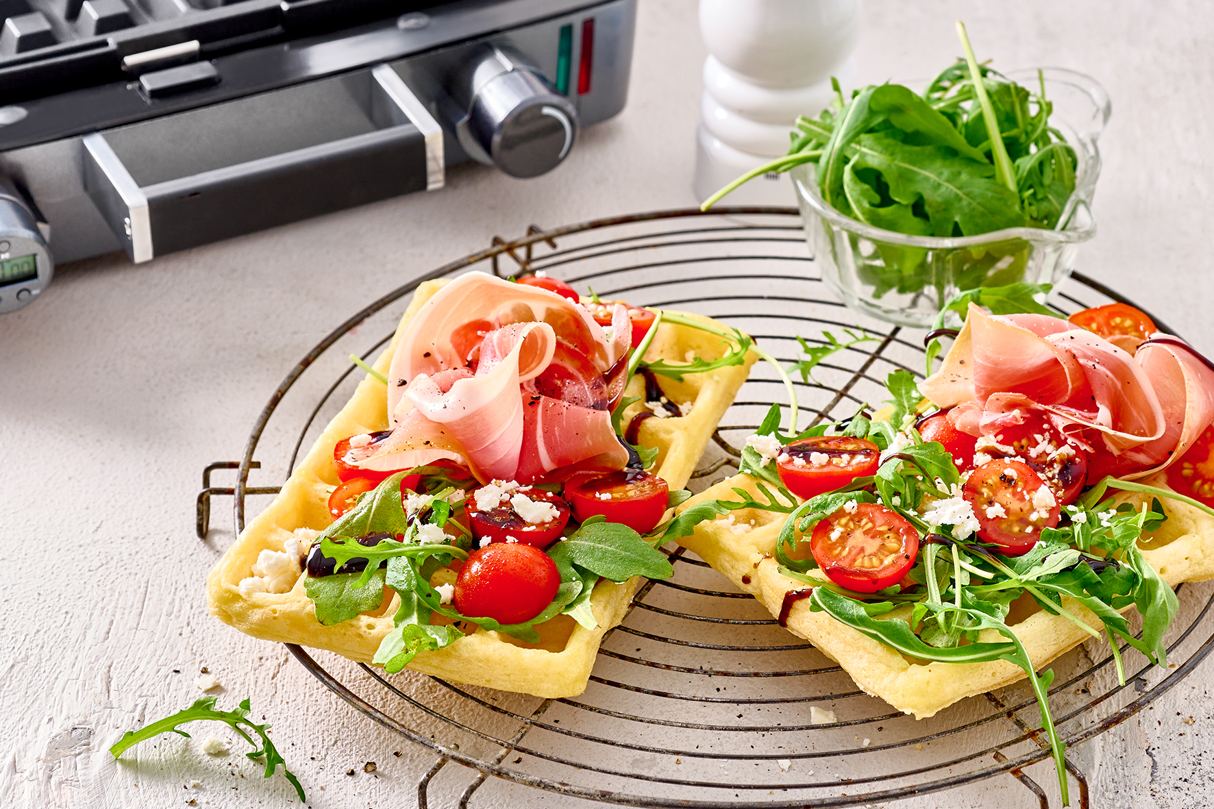 Waffle con prosciutto, pomodorini, rucola e formaggio su gratella.