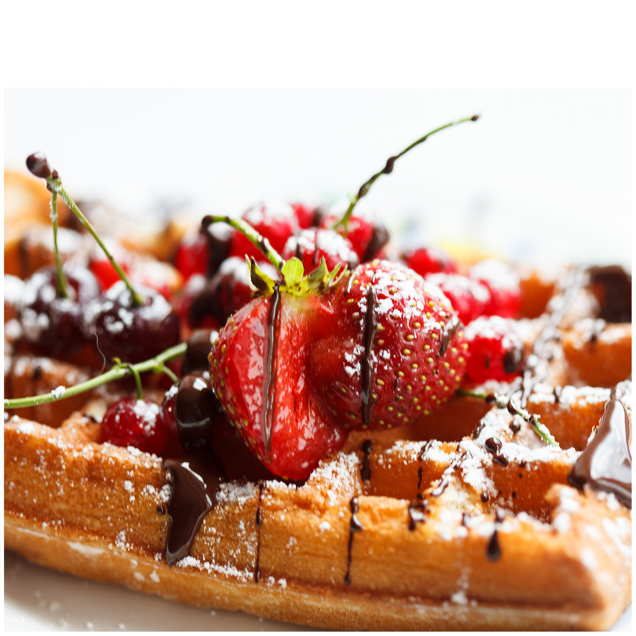 Un waffle con bacche, cioccolato e zucchero a velo.
