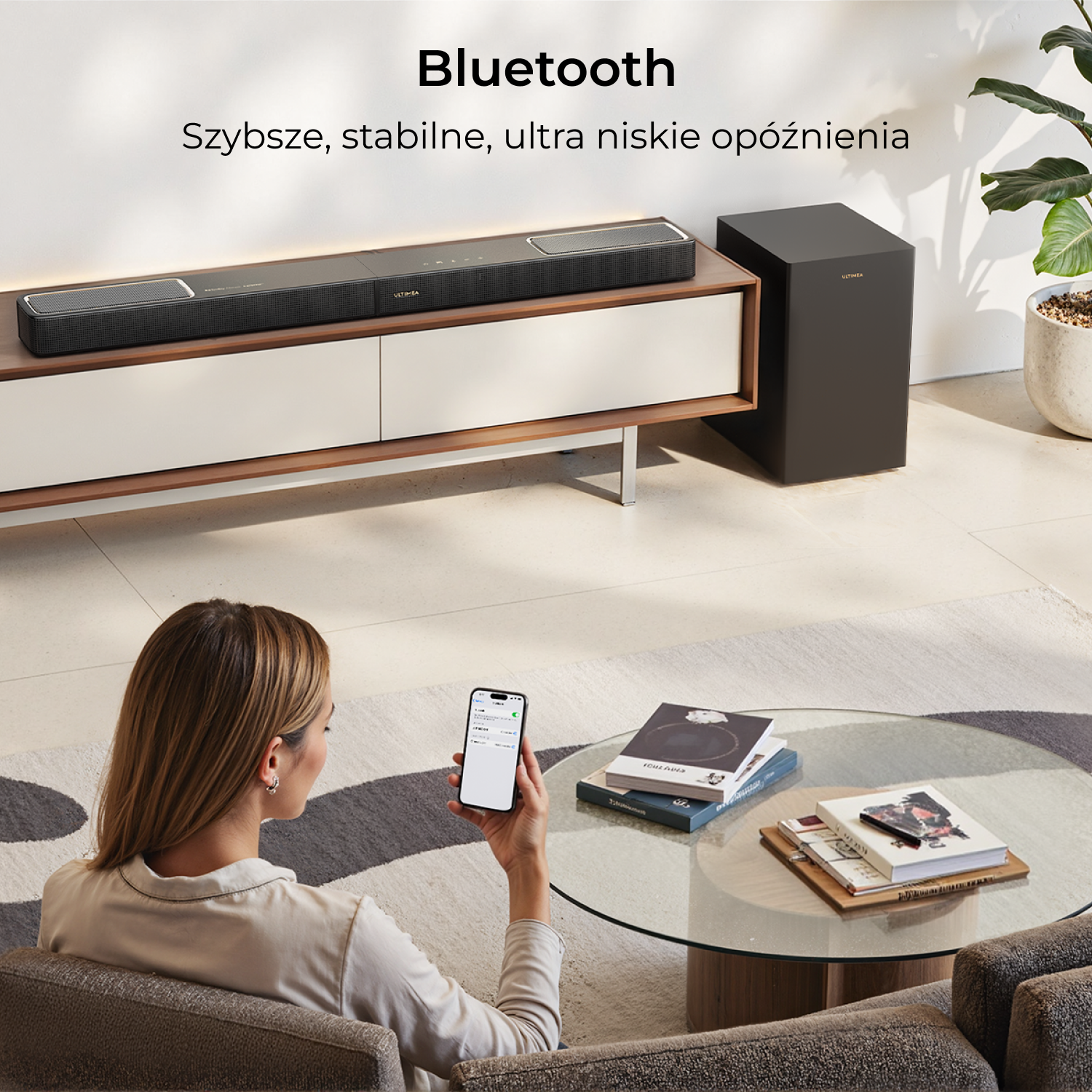 Nowoczesna soundbar i subwoofer na komodzie, kobieta używa smartfona.