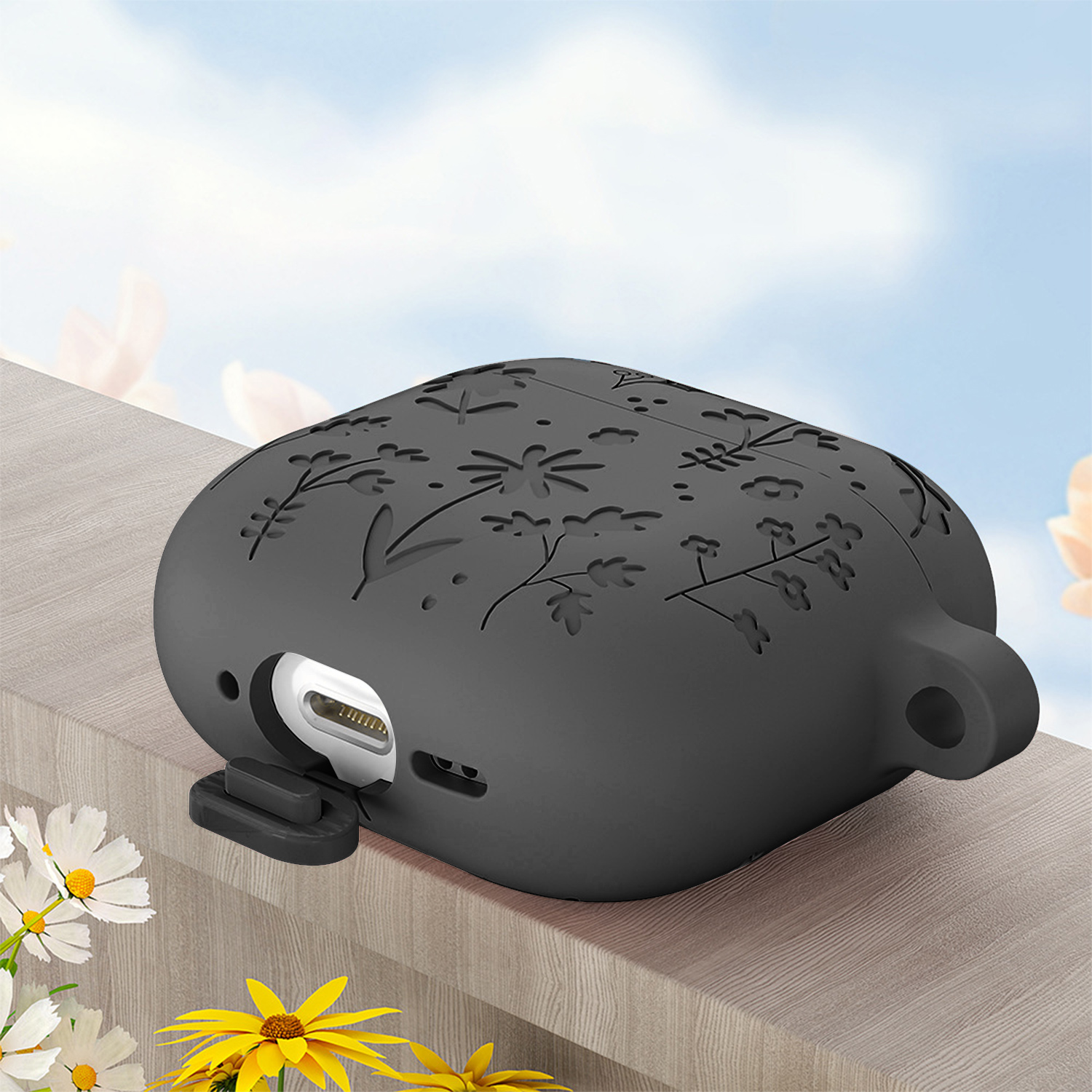 Funda gris para AirPods con estampado floral sobre mesa de madera.