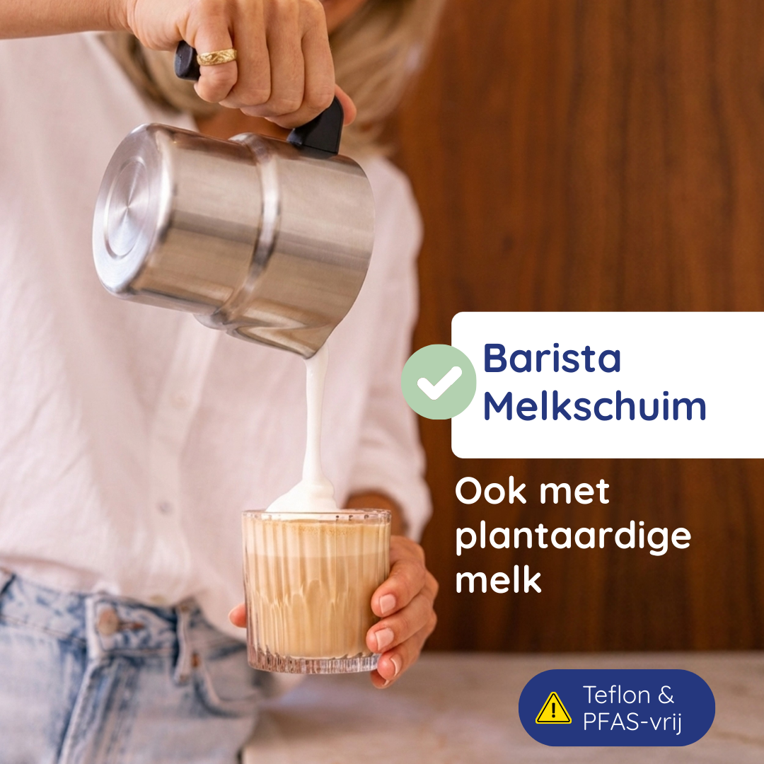Een persoon schenkt melkschuim uit een metalen kannetje in een glas.