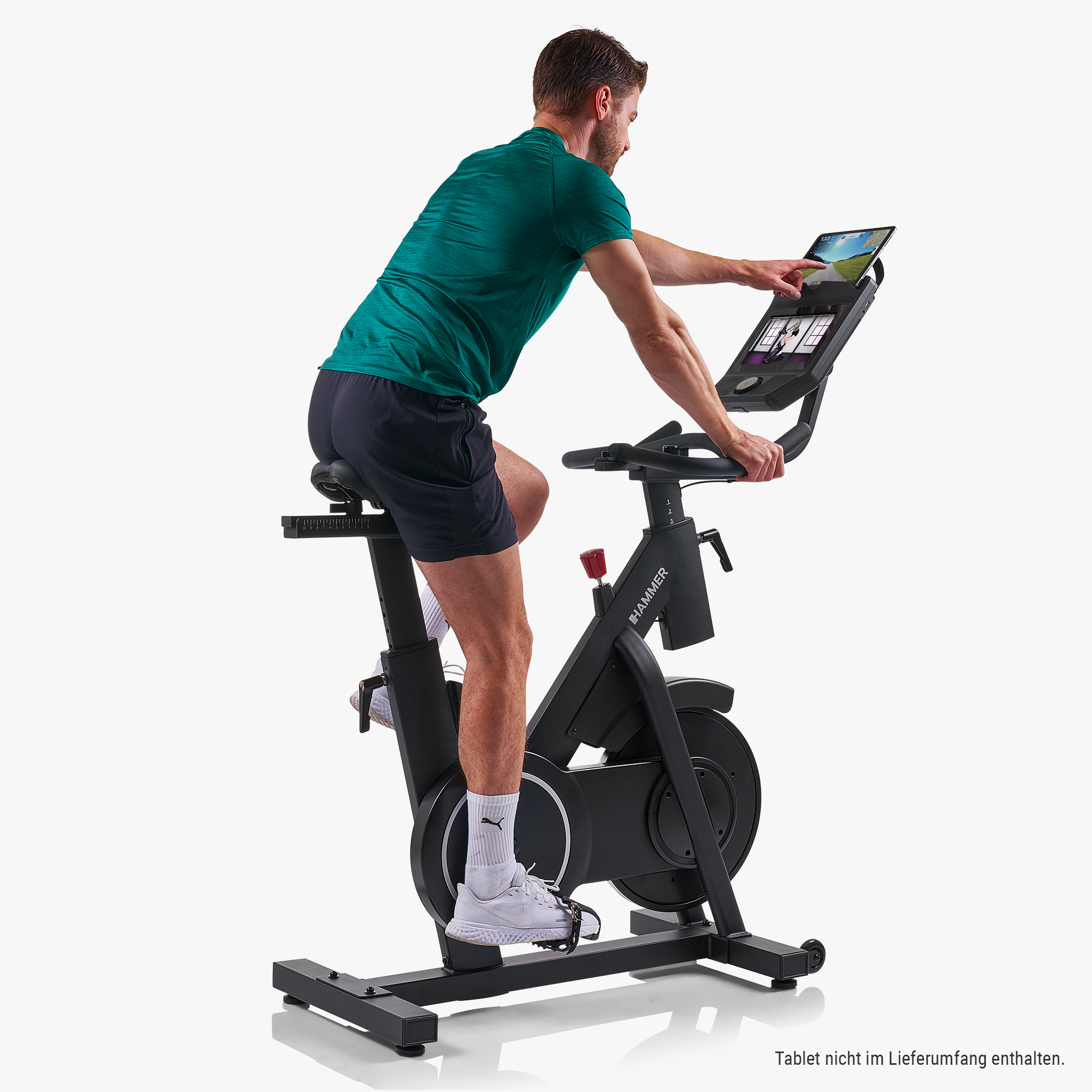 Mann auf einem Heimtrainer, der auf ein Tablet tippt.