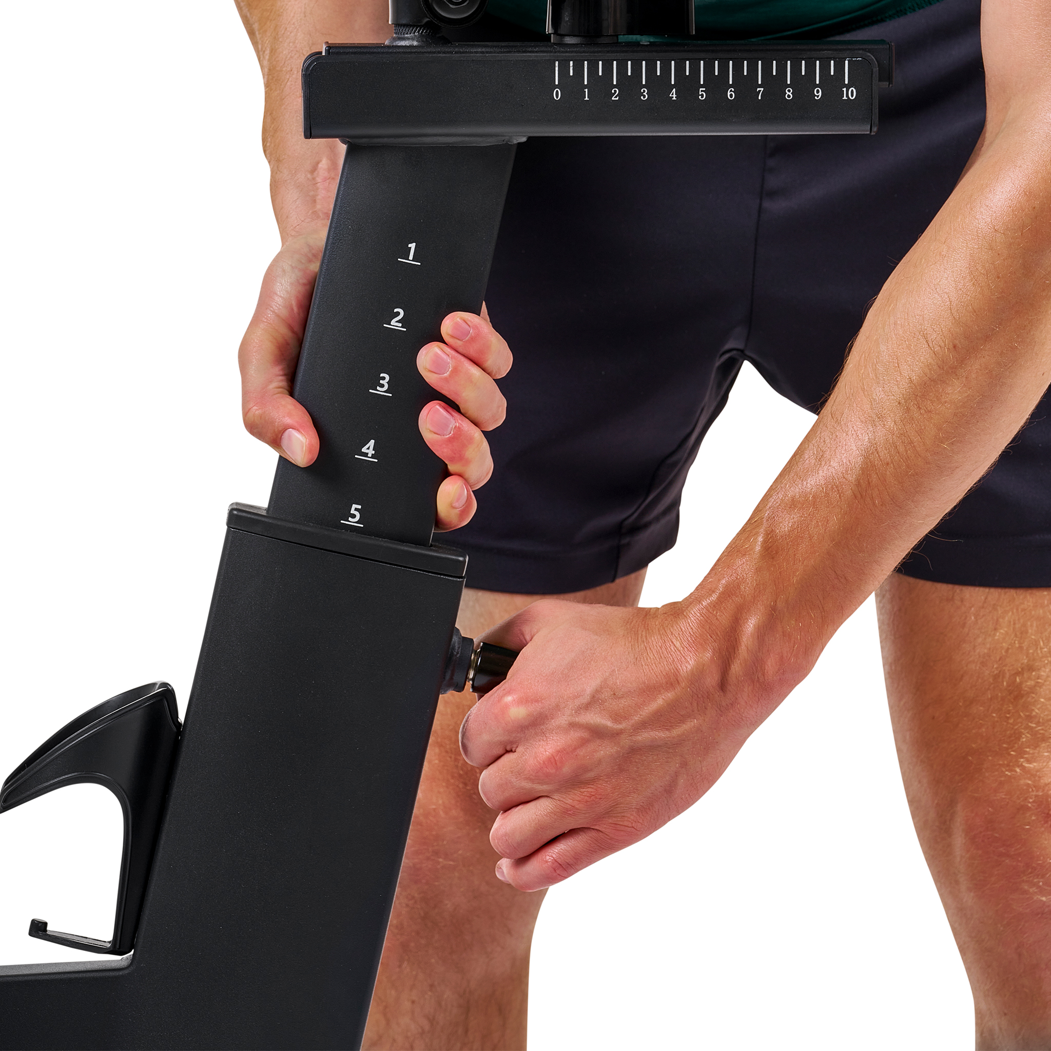 Eine Person verstellt ein schwarzes Fitnessgerät mit nummerierten Markierungen und einem Rad.