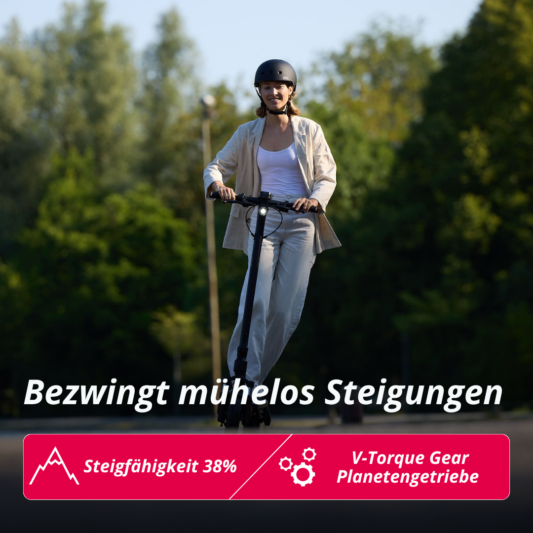 Eine Frau fährt einen E-Scooter mit Helm auf einer Straße im Freien.