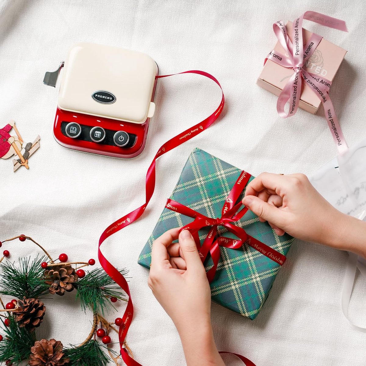 Mains nouant un ruban rouge "Merry Christmas" autour d'un cadeau.