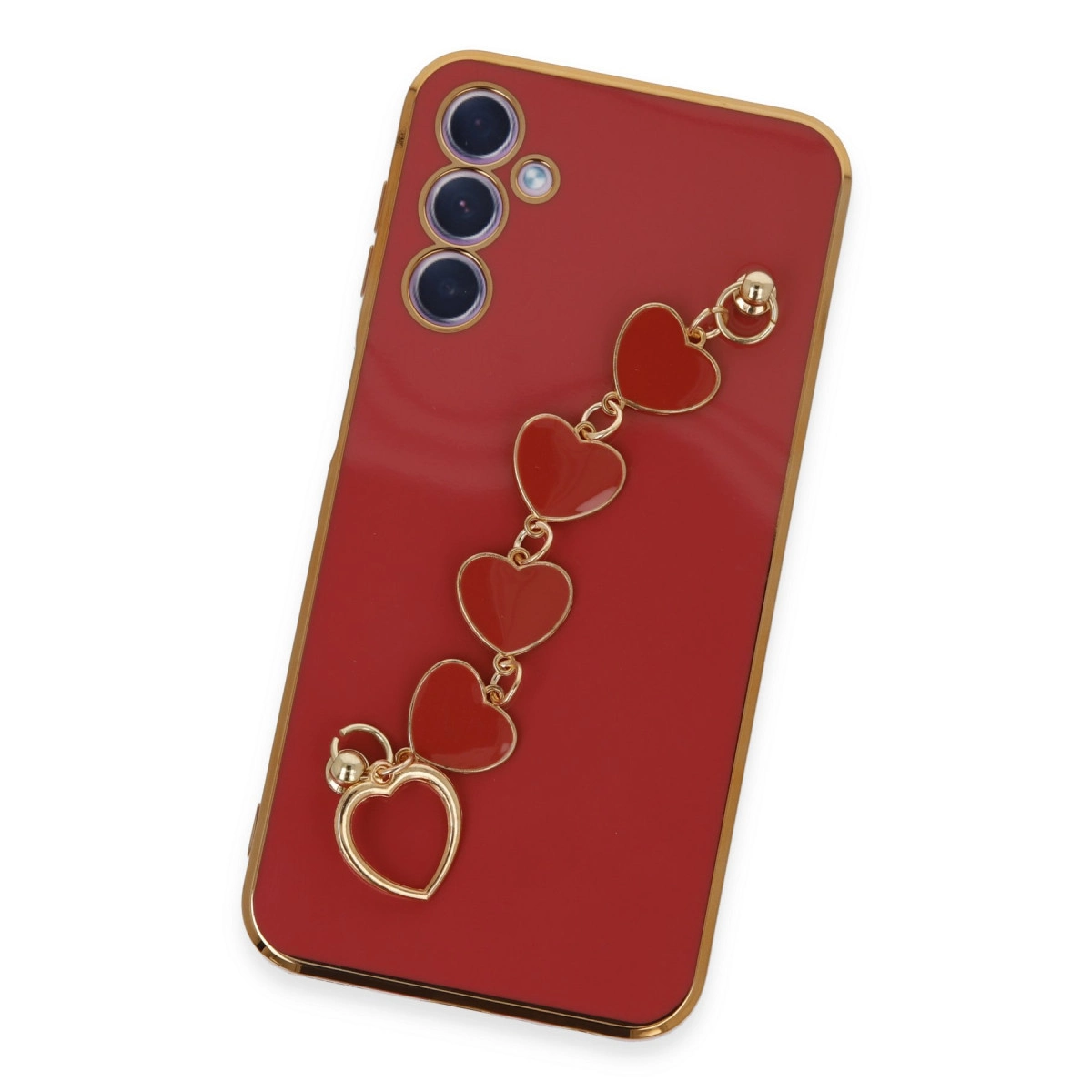 Altın kenarlı kırmızı telefon kılıfı, kalp şeklinde takı. Kamera modülü sol üstte.