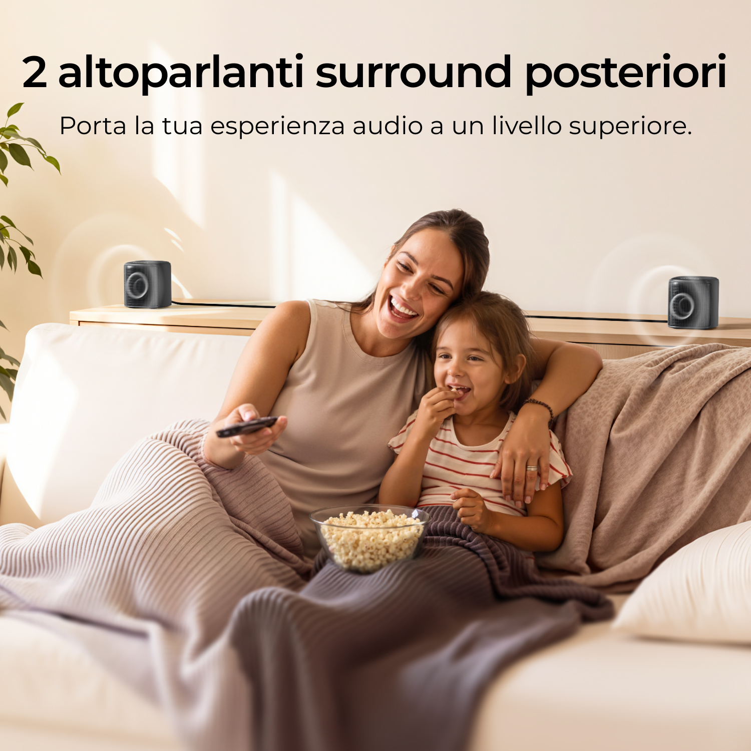 Donna e bambina su divano con popcorn, due altoparlanti sullo sfondo.