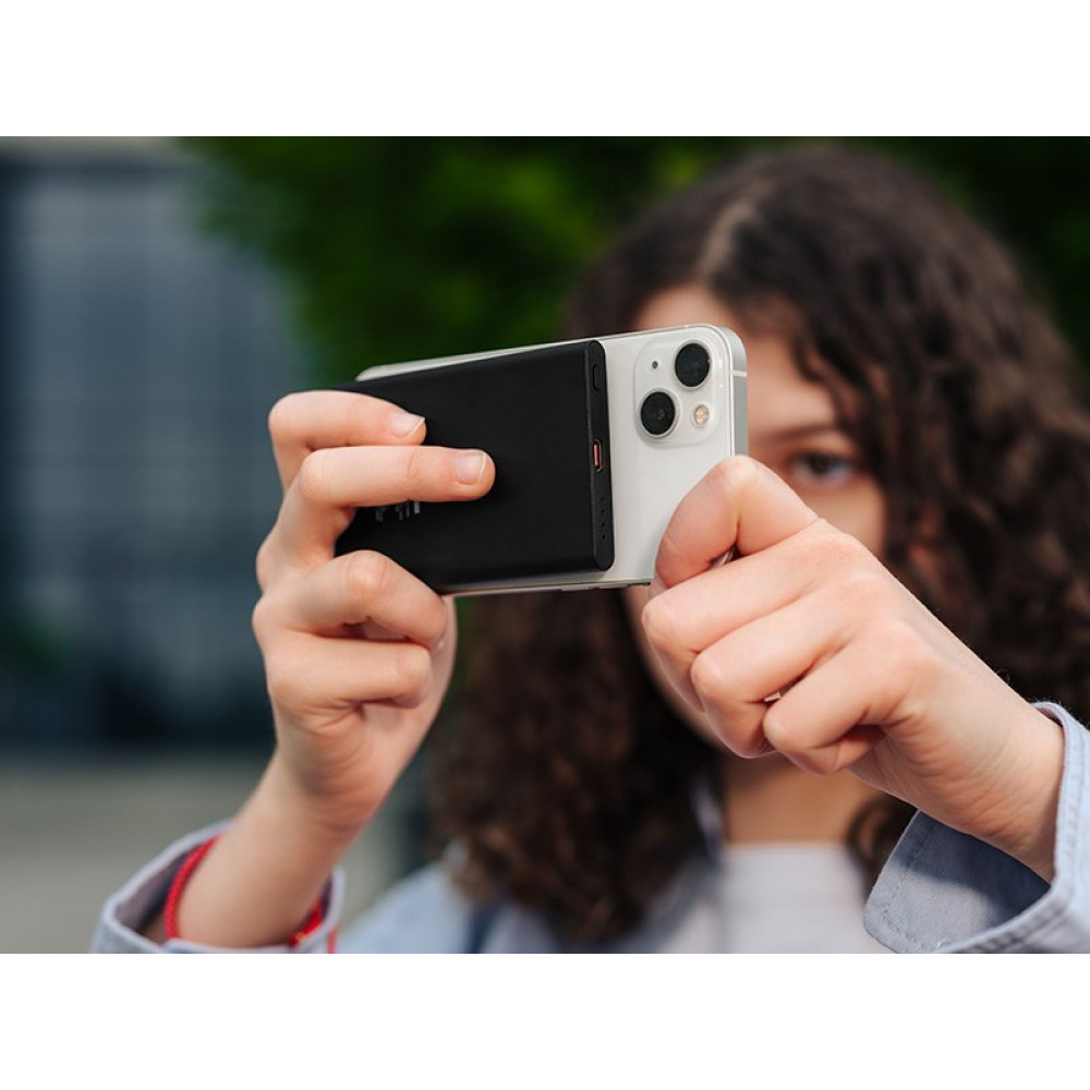 Osoba trzyma w dłoniach smartfon i powerbank.