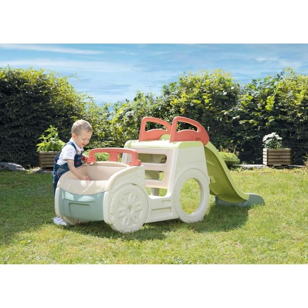 Un bambino gioca con uno scivolo a macchinina in un giardino.