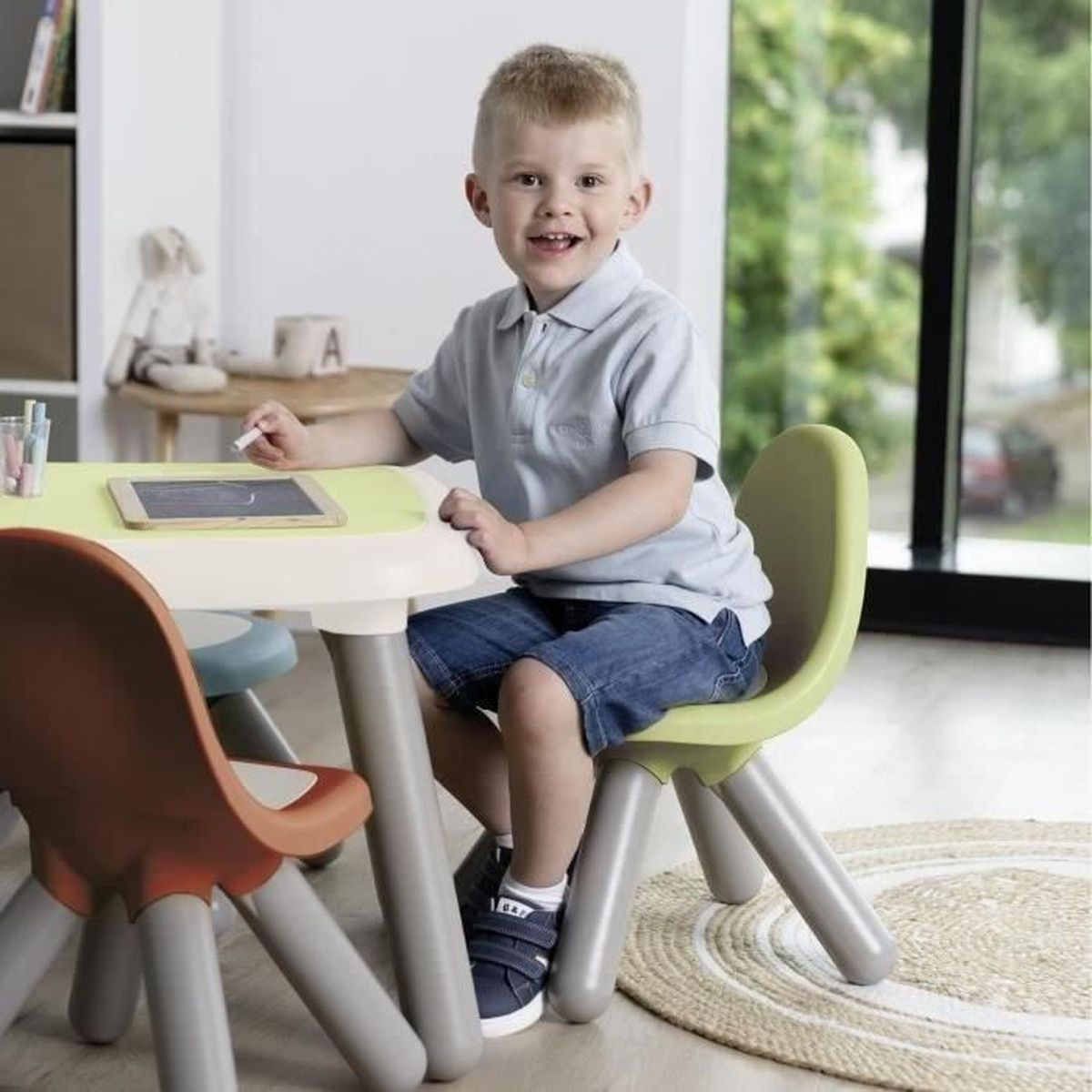 Ein Junge sitzt an einem Kindertisch und malt mit Kreide.