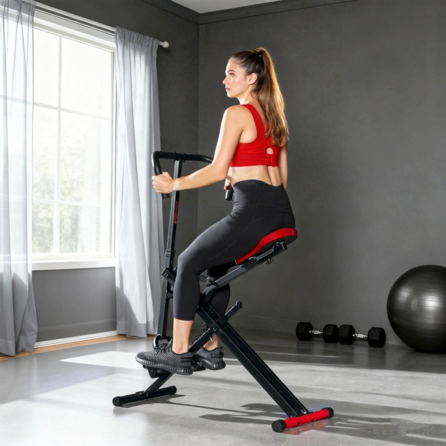 Frau trainiert auf Heimtrainer mit Hanteln und Gymnastikball im Hintergrund.