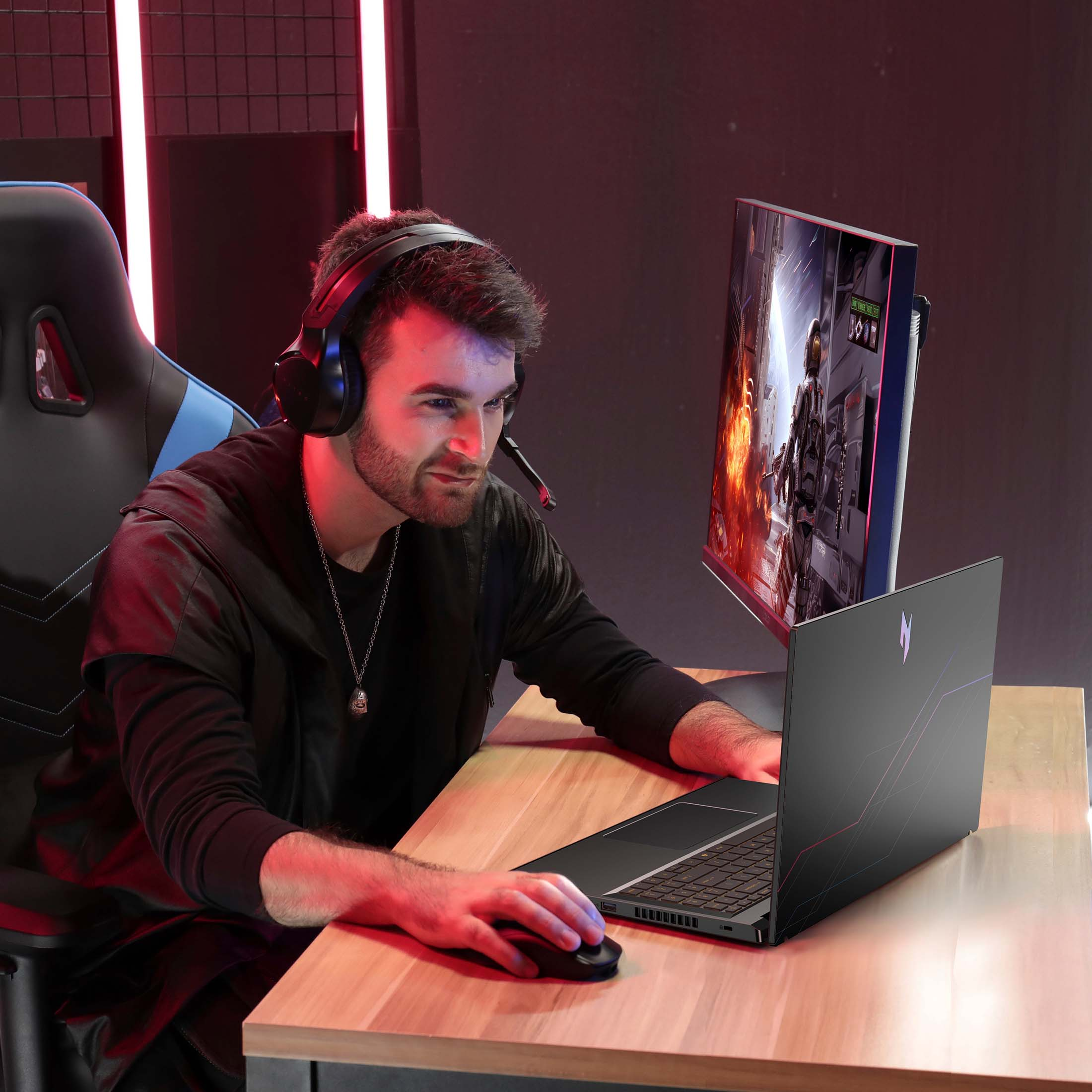 Un homme portant un casque joue à un jeu vidéo sur un ordinateur portable et un écran.