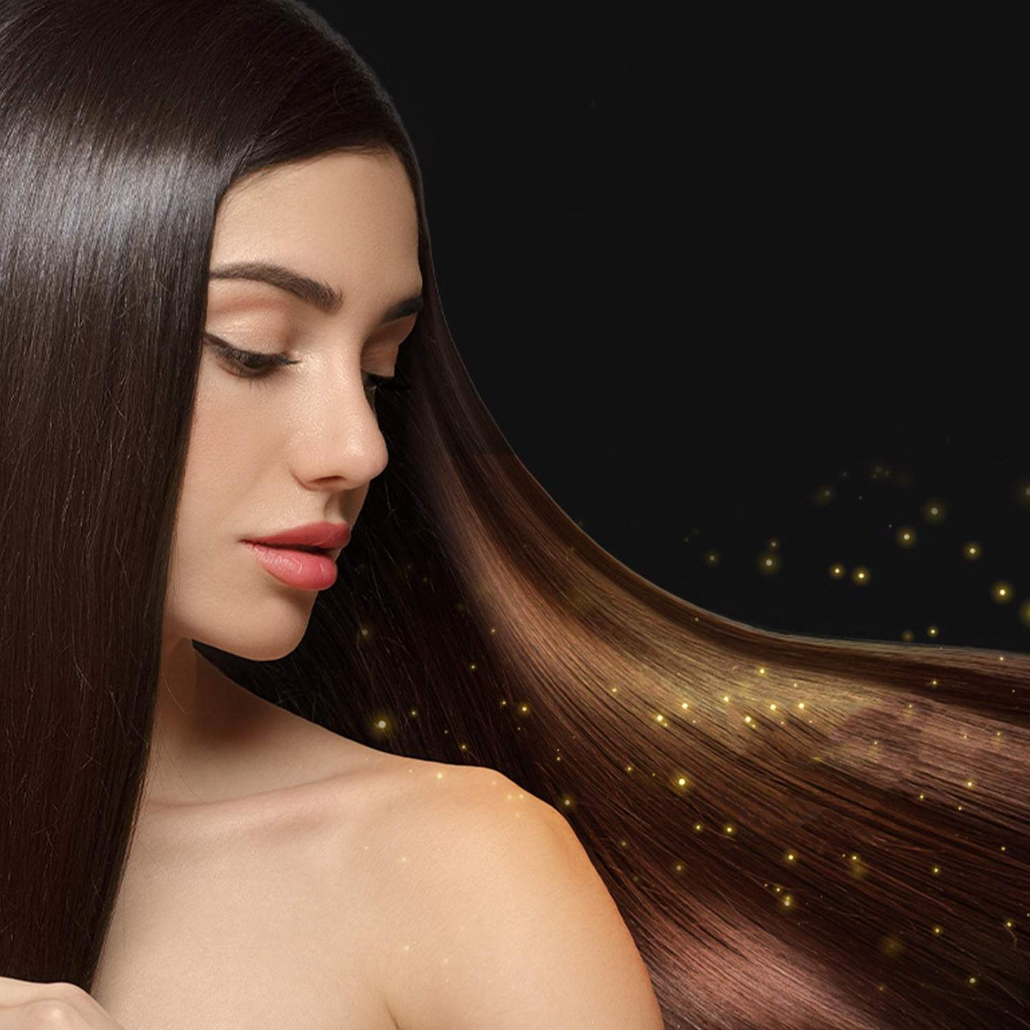 Frau mit langen, glänzenden braunen Haaren und goldenen Glitzerpartikeln auf schwarzem Hintergrund.