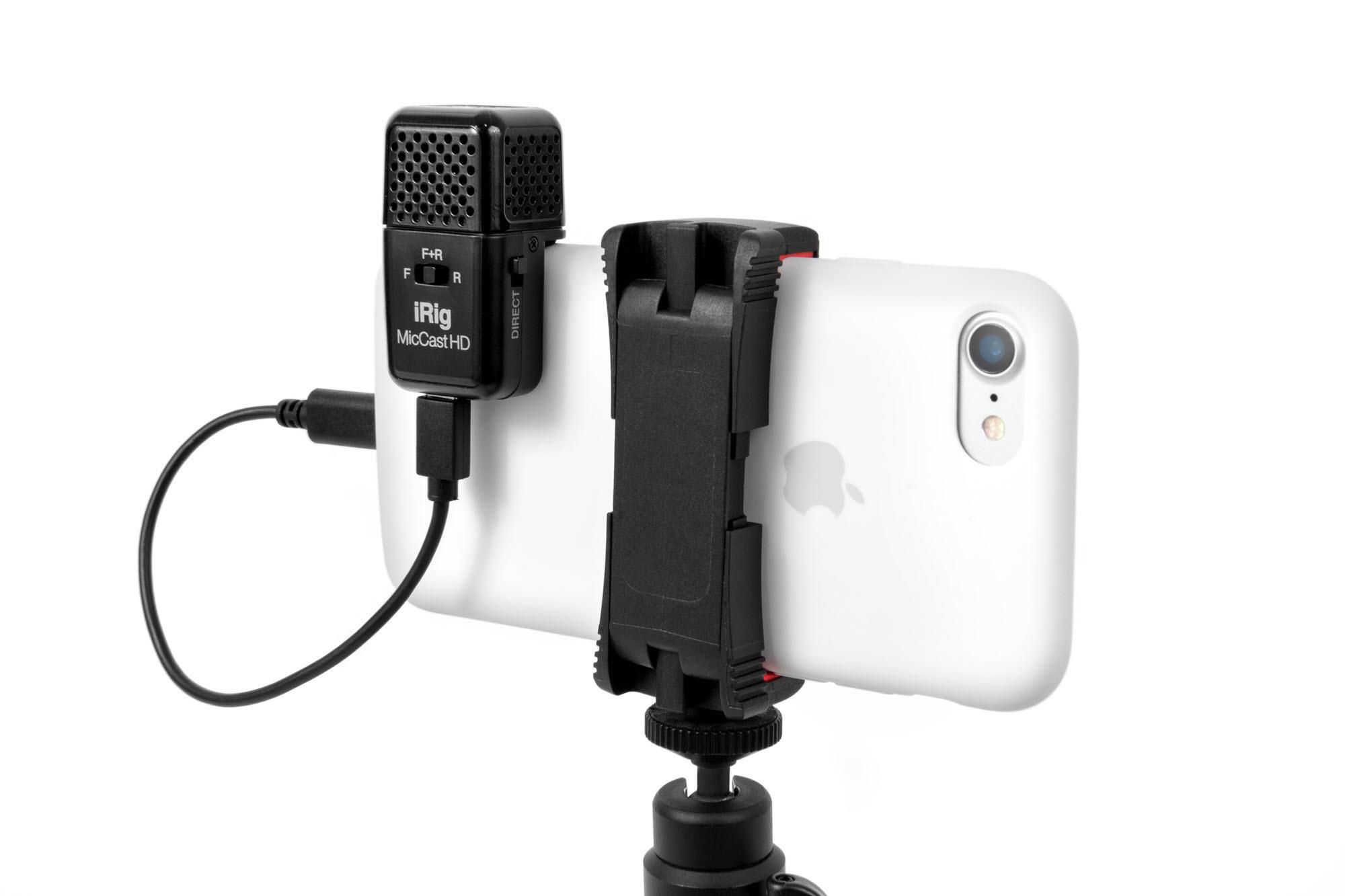 Ein schwarzes iRig-Mikrofon ist über eine Klemme an einem weißen iPhone befestigt. Ein Kabel verbindet das Mikrofon mit dem Telefon.