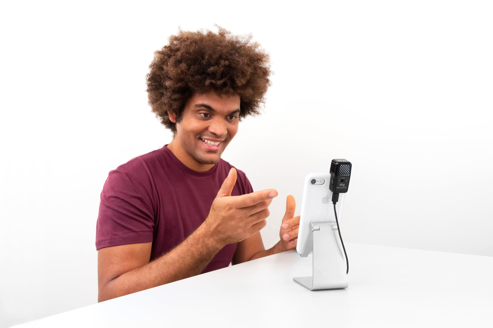 Mann mit Afro-Frisur spricht in ein Mikrofon, das an einem Smartphone befestigt ist.