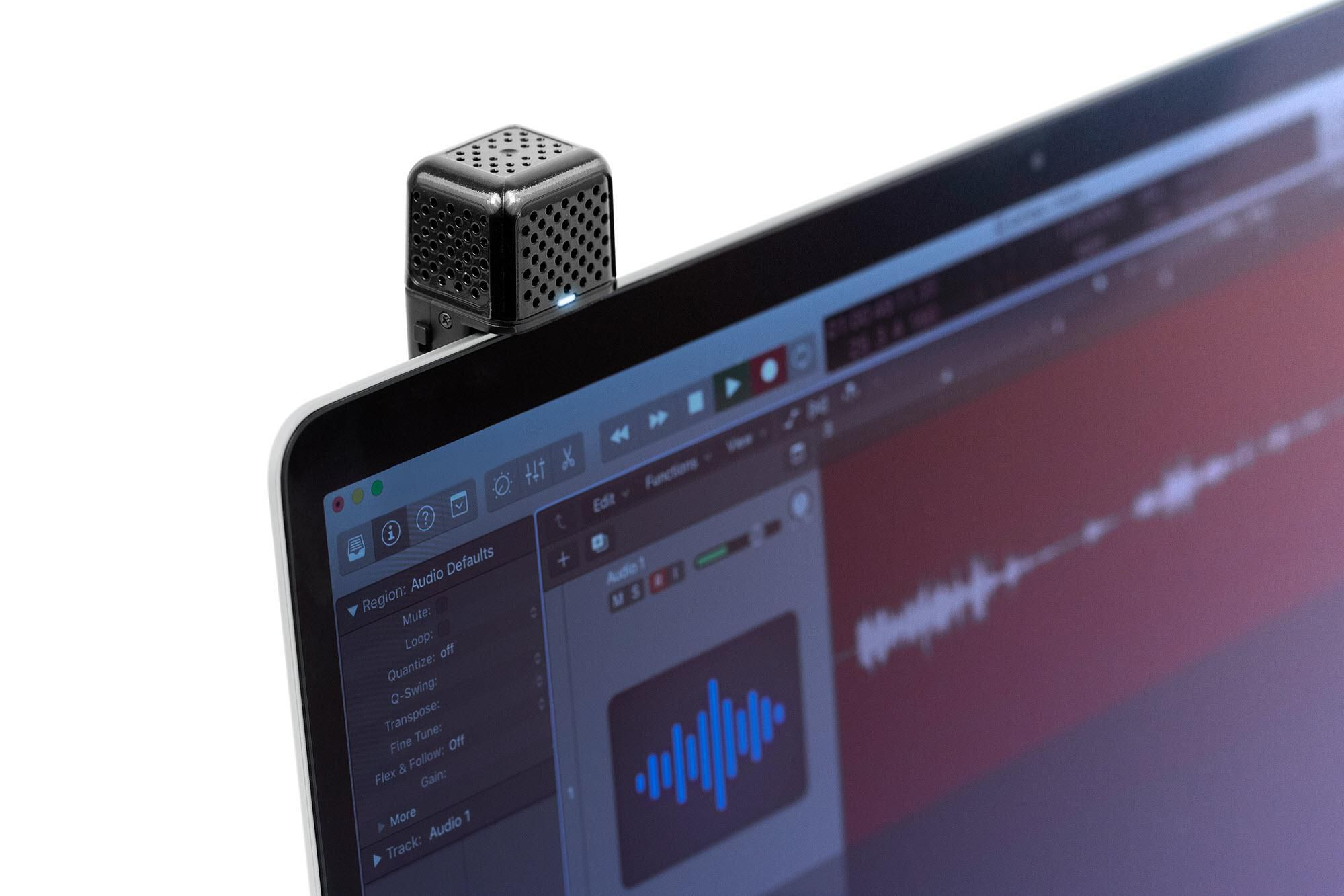 Ein schwarzes Mikrofon ist an einem Laptop befestigt, der eine Audio-Software anzeigt.