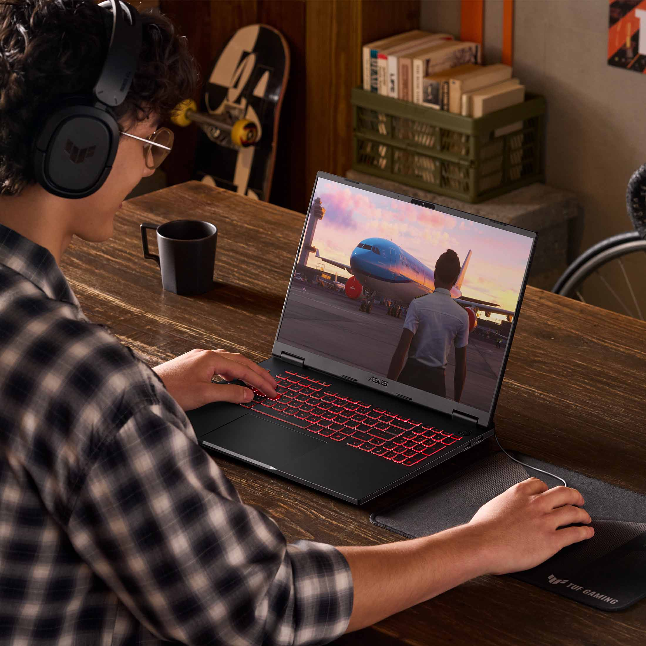 Mann mit Kopfhörern spielt am Laptop, der ein Flugzeug zeigt.