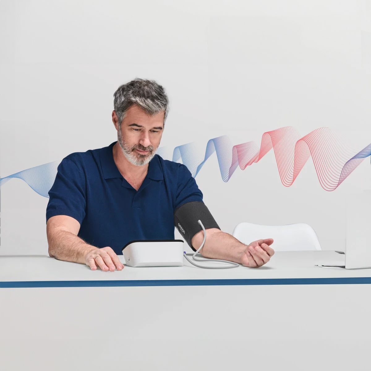 Mężczyzna z siwymi włosami używa białego urządzenia do pomiaru ciśnienia krwi.