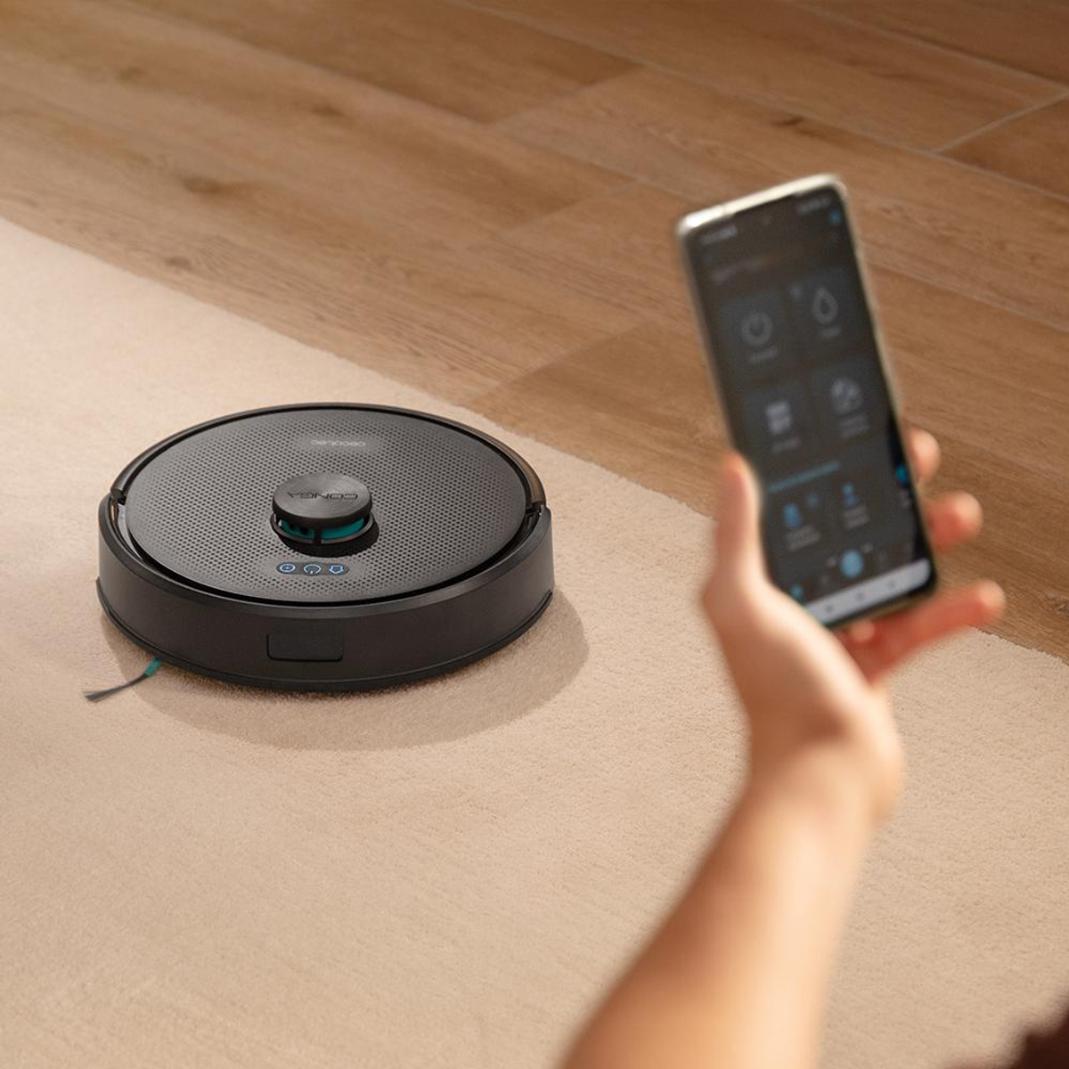 Un robot aspirapolvere su tappeto è controllato via smartphone.