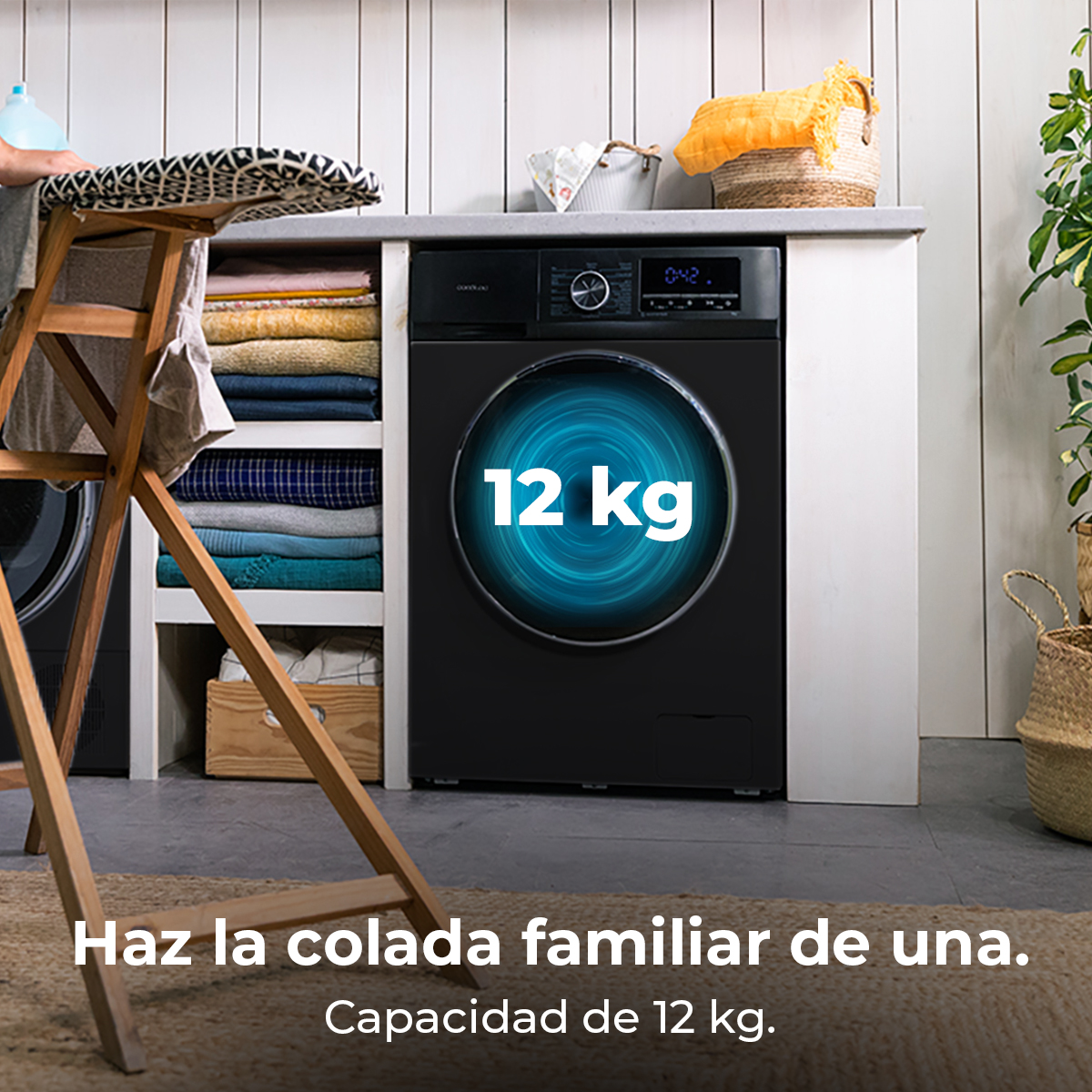 Una lavatrice nera da 12 kg, accanto a uno stendibiancheria con vestiti.