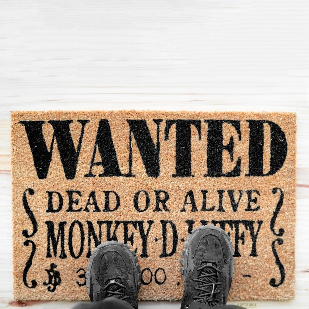 Felpudo con el texto "WANTED DEAD OR ALIVE MONKEY DUFFY" y dos zapatos grises.