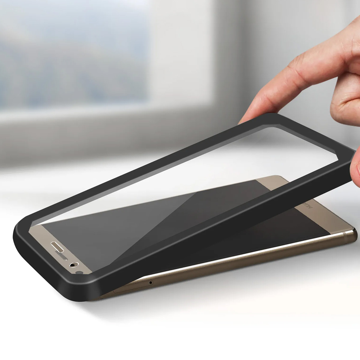 Una mano posa una custodia nera su uno smartphone dorato.