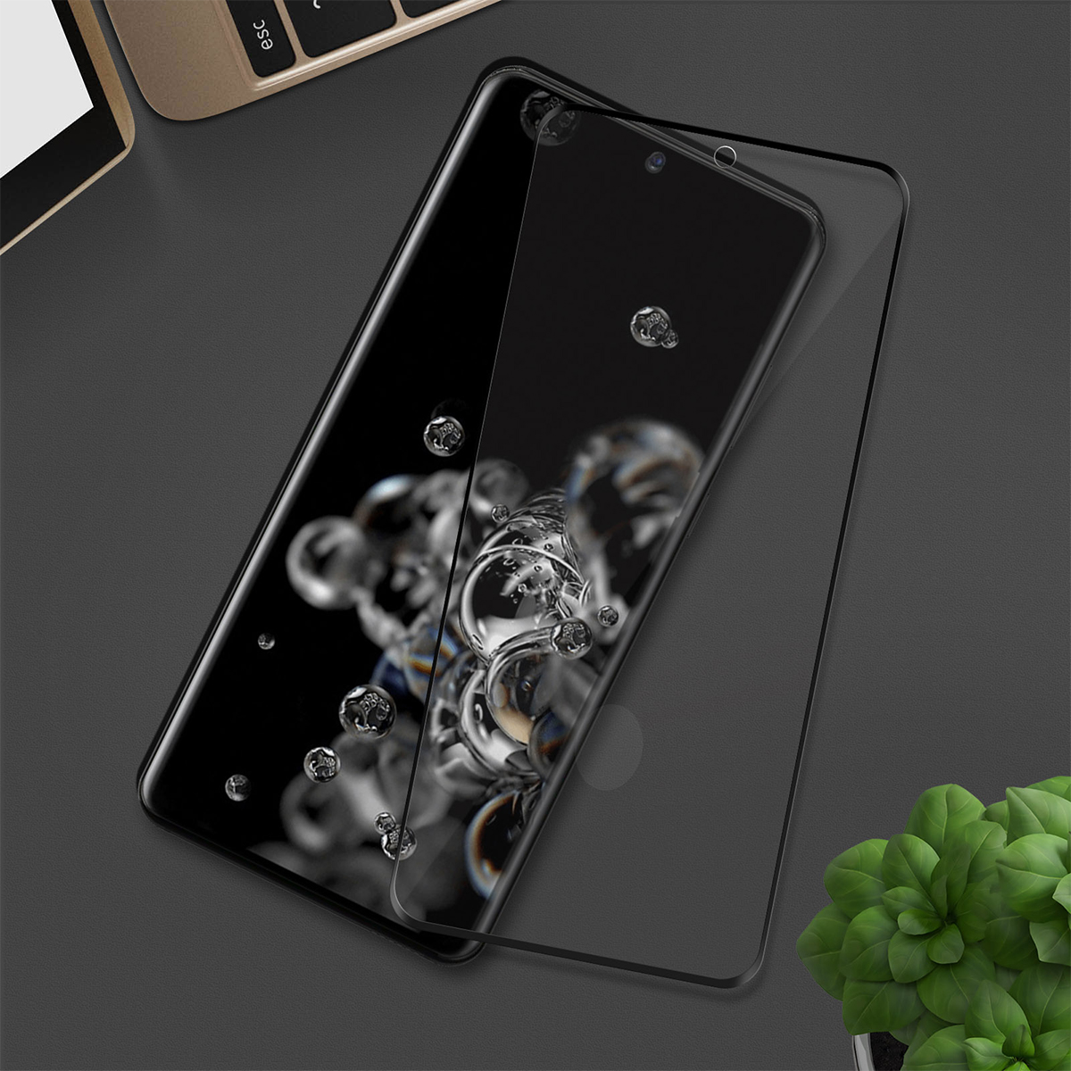 Uno smartphone con proteggischermo su una scrivania scura.