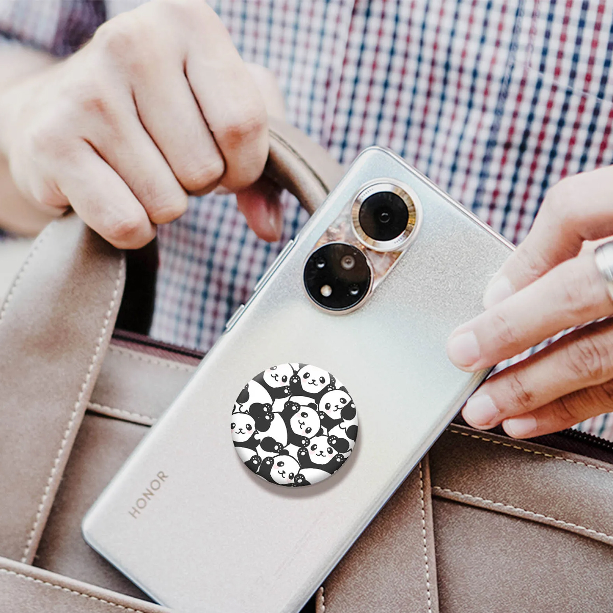 Un teléfono con un pop socket de panda se está guardando en un bolso.