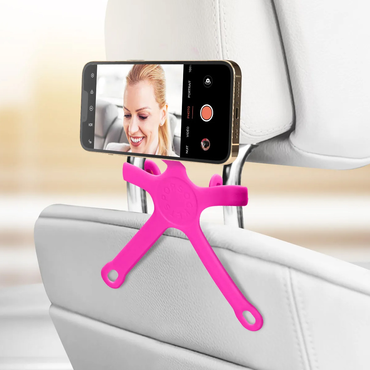 Un porta telefono rosa tiene uno smartphone davanti a un sedile dell'auto bianco.