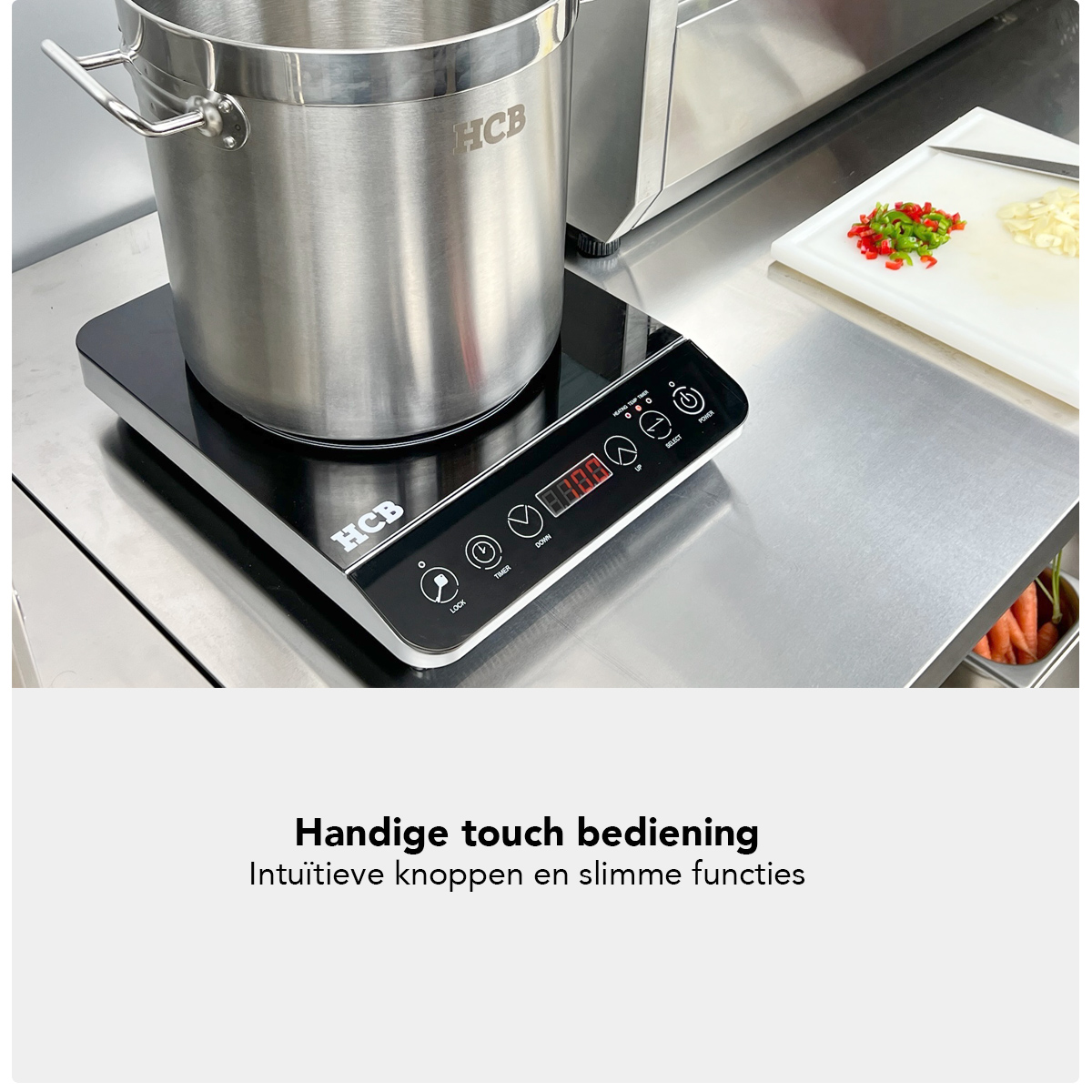 Een grote pan op een inductiekookplaat met touch bedieningspaneel. Gehakte chilipepers en knoflook ernaast.