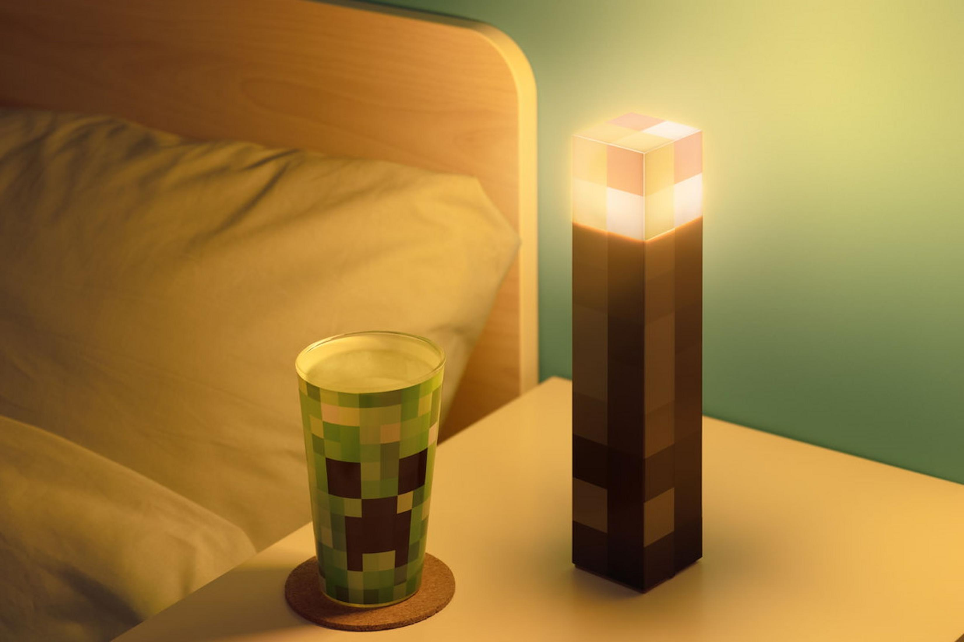 Ein Minecraft Creeper-Becher und eine Fackel-Lampe auf einem Nachttisch.
