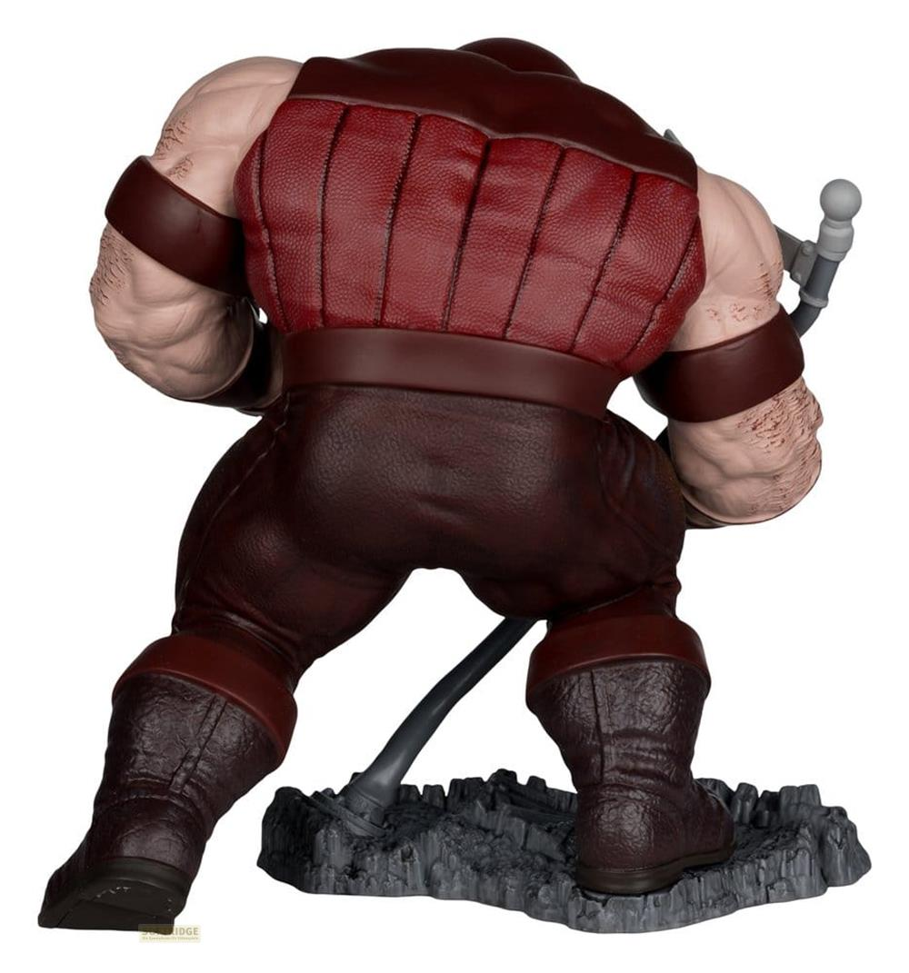 Die Rückansicht einer muskulösen Figur in brauner Kleidung, die auf einem felsigen Sockel steht.