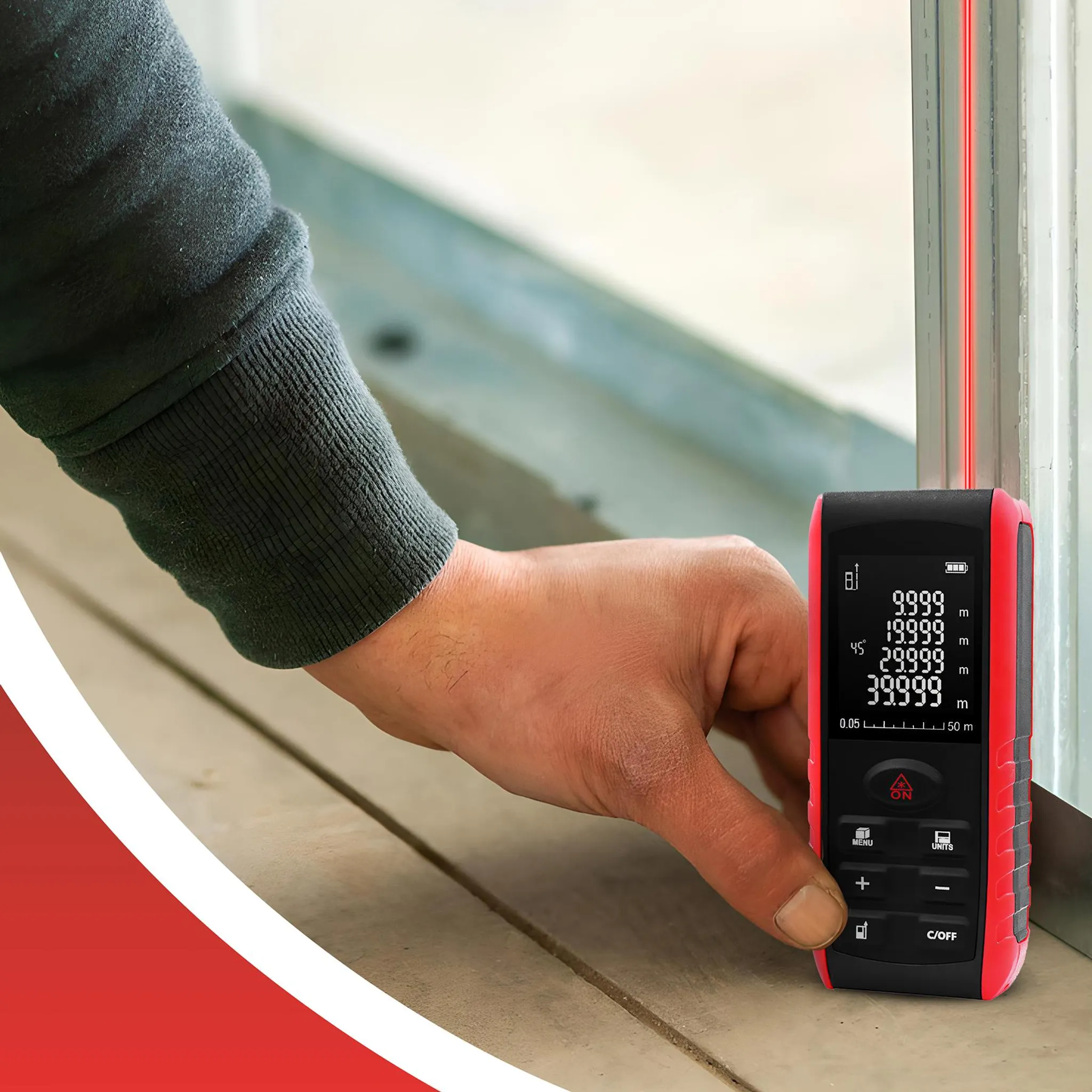 Eine Hand hält ein rotes digitales Maßband mit einem roten Laserstrahl.
