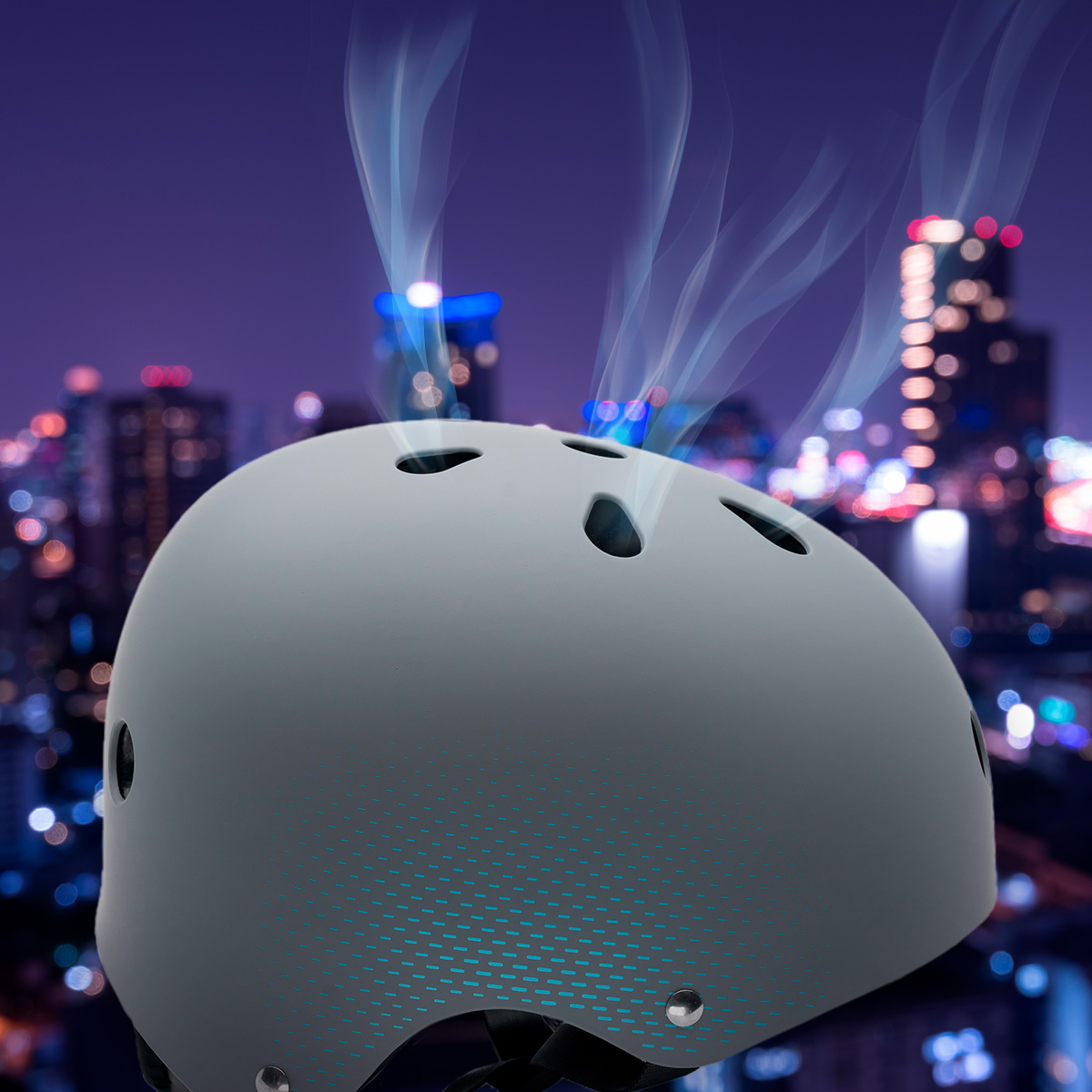 Casco gris con ventilaciones, contra un borroso horizonte urbano nocturno.