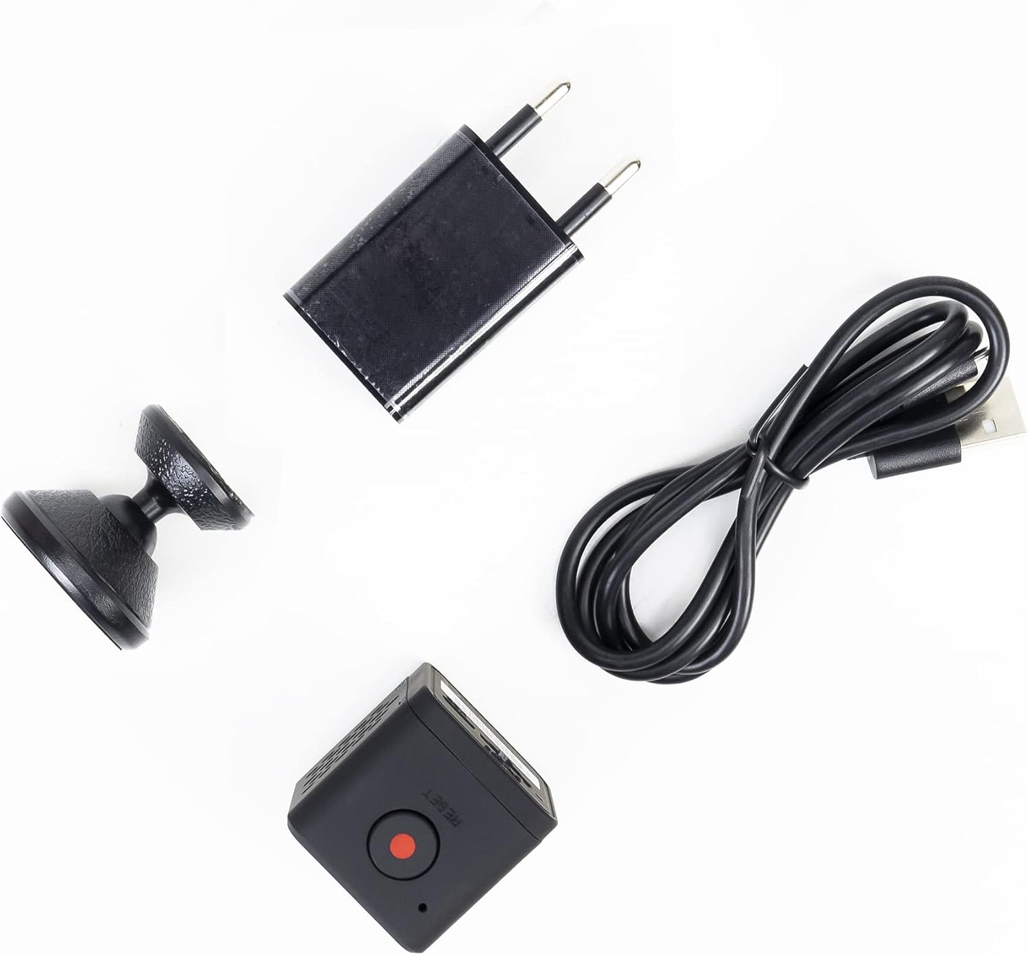 Ein schwarzer USB-Adapter, ein Ladekabel und eine kleine Kamera auf weißem Hintergrund.