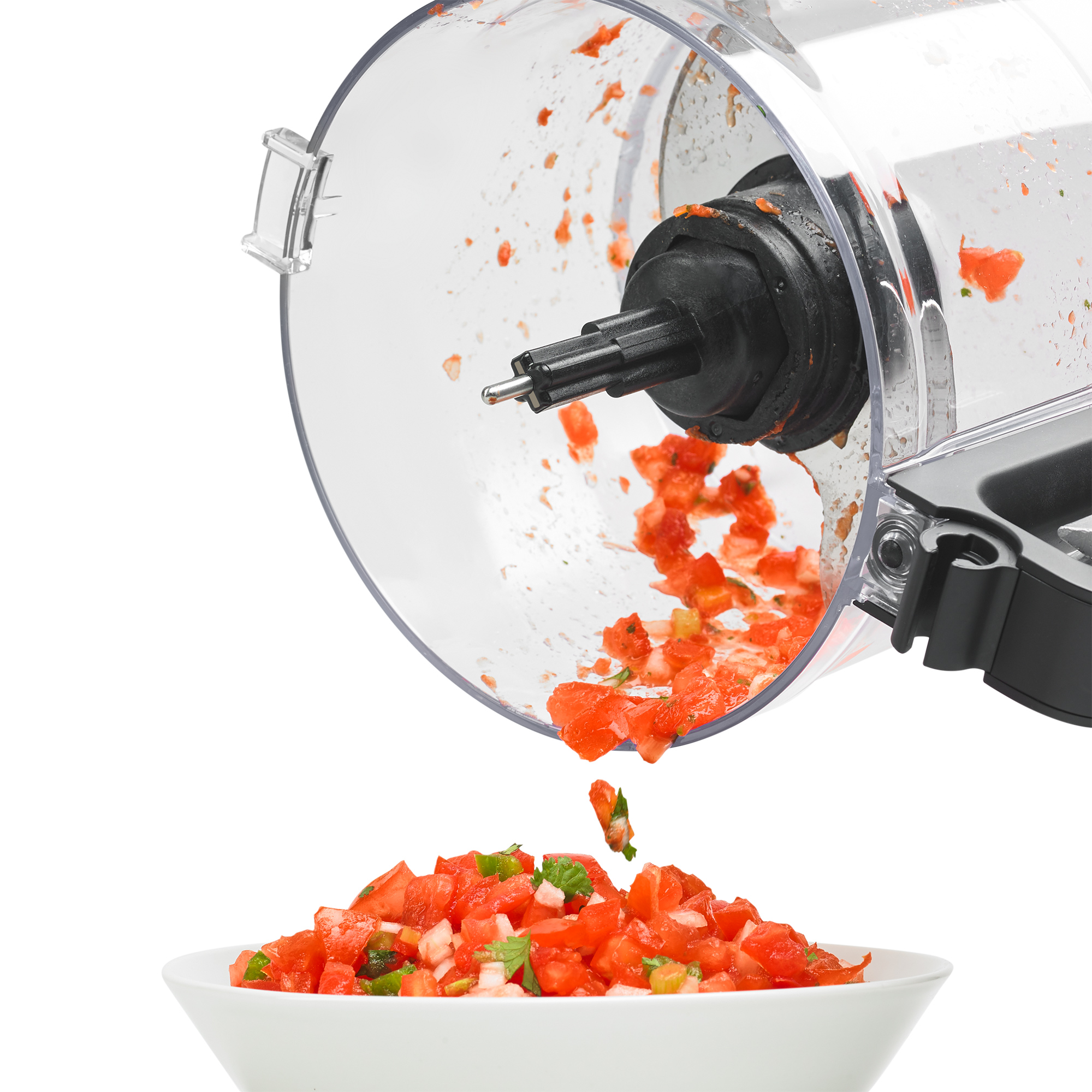 Gehackte Tomaten fallen aus einem Mixer in eine weiße Schüssel.