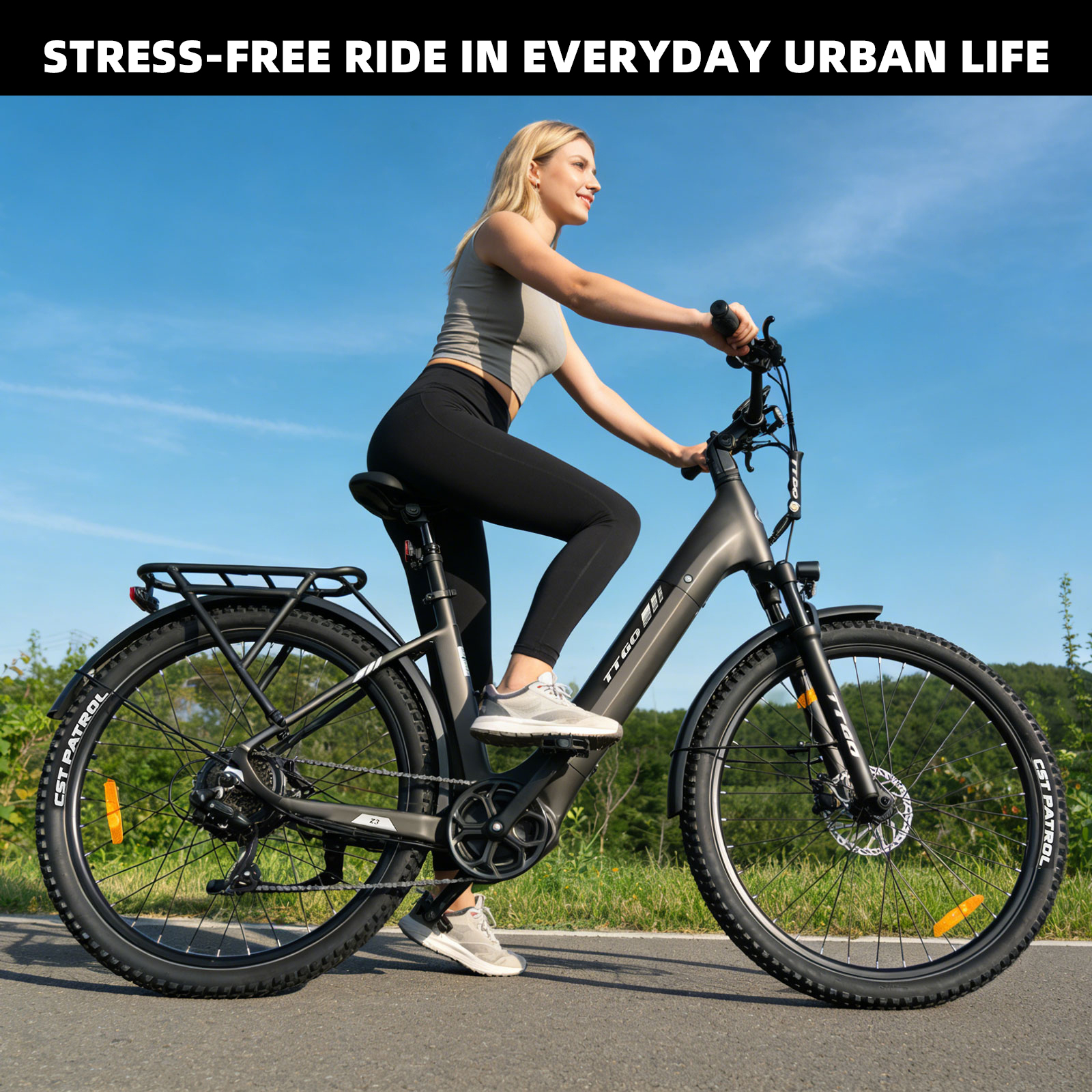 Kobieta jedzie ciemnym rowerem elektrycznym po asfaltowej drodze pod błękitnym niebem.