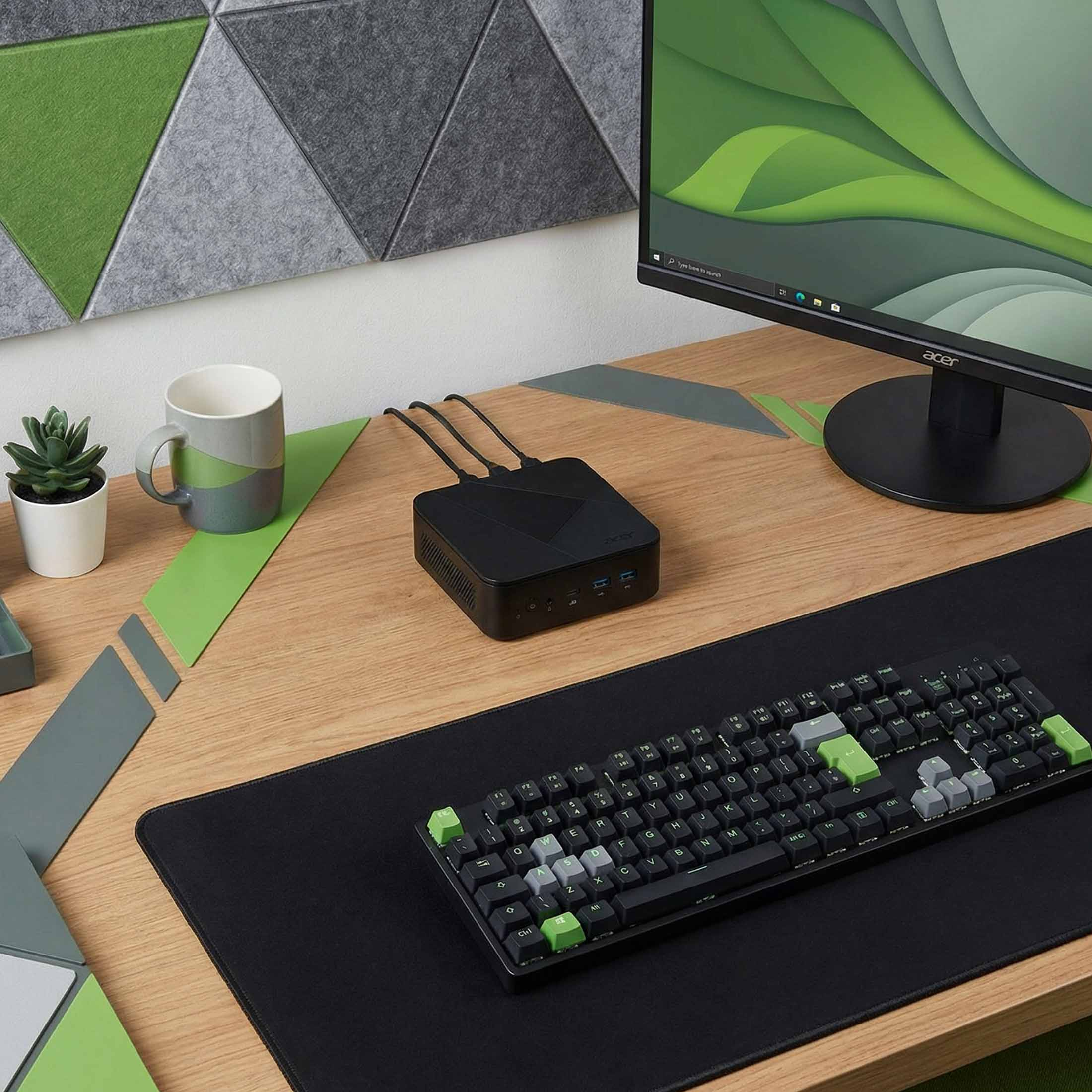 Schwarzer Mini-PC auf einem Holztisch mit Tastatur, Monitor und Pflanze.