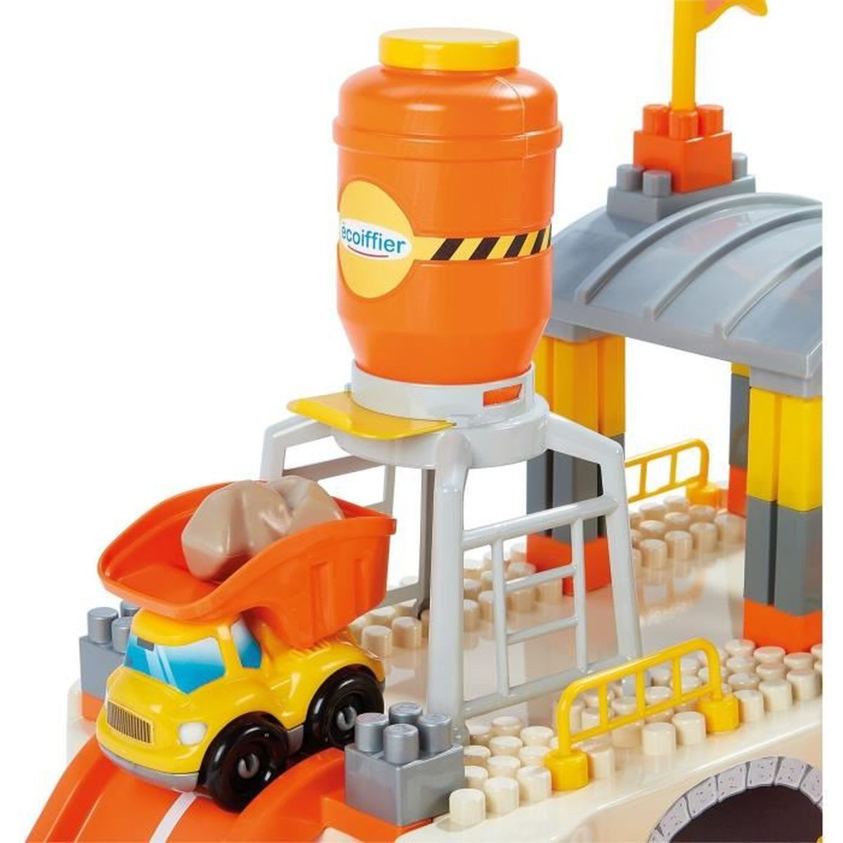 Ein gelber Spielzeugkipper mit Steinen unter einem orangefarbenen Behälter.