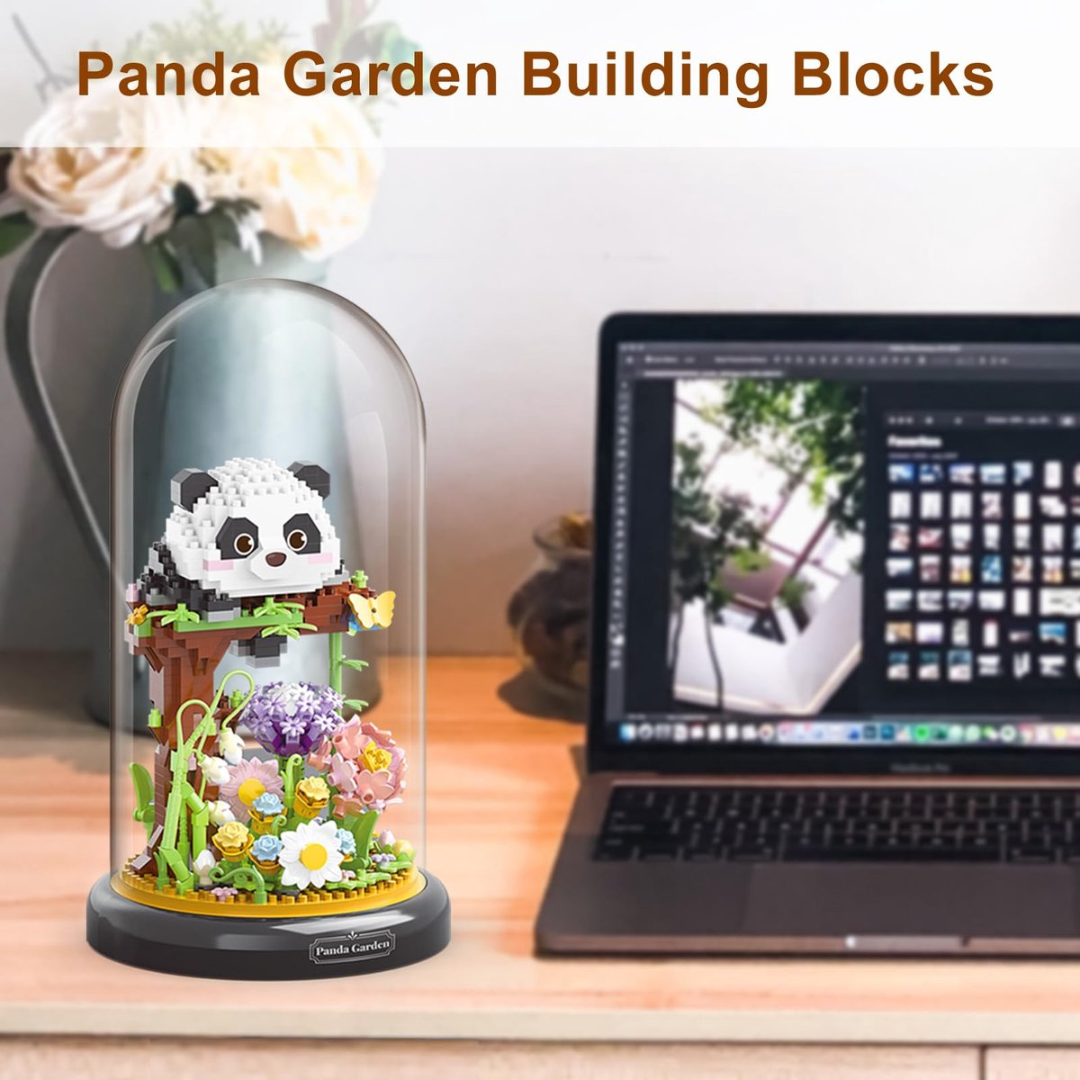 Ein Panda-Bausatz mit Blumen unter einer Glasglocke auf einem Schreibtisch.