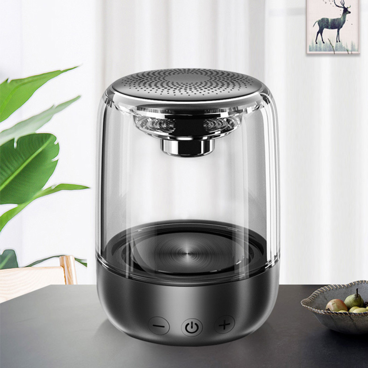 Przezroczysty głośnik z czarną podstawą stoi na stole.