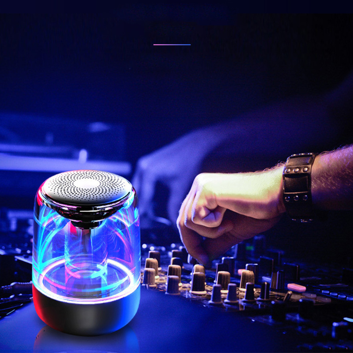 Świecący głośnik na konsolecie mikserskiej, obsługiwany przez dłoń.