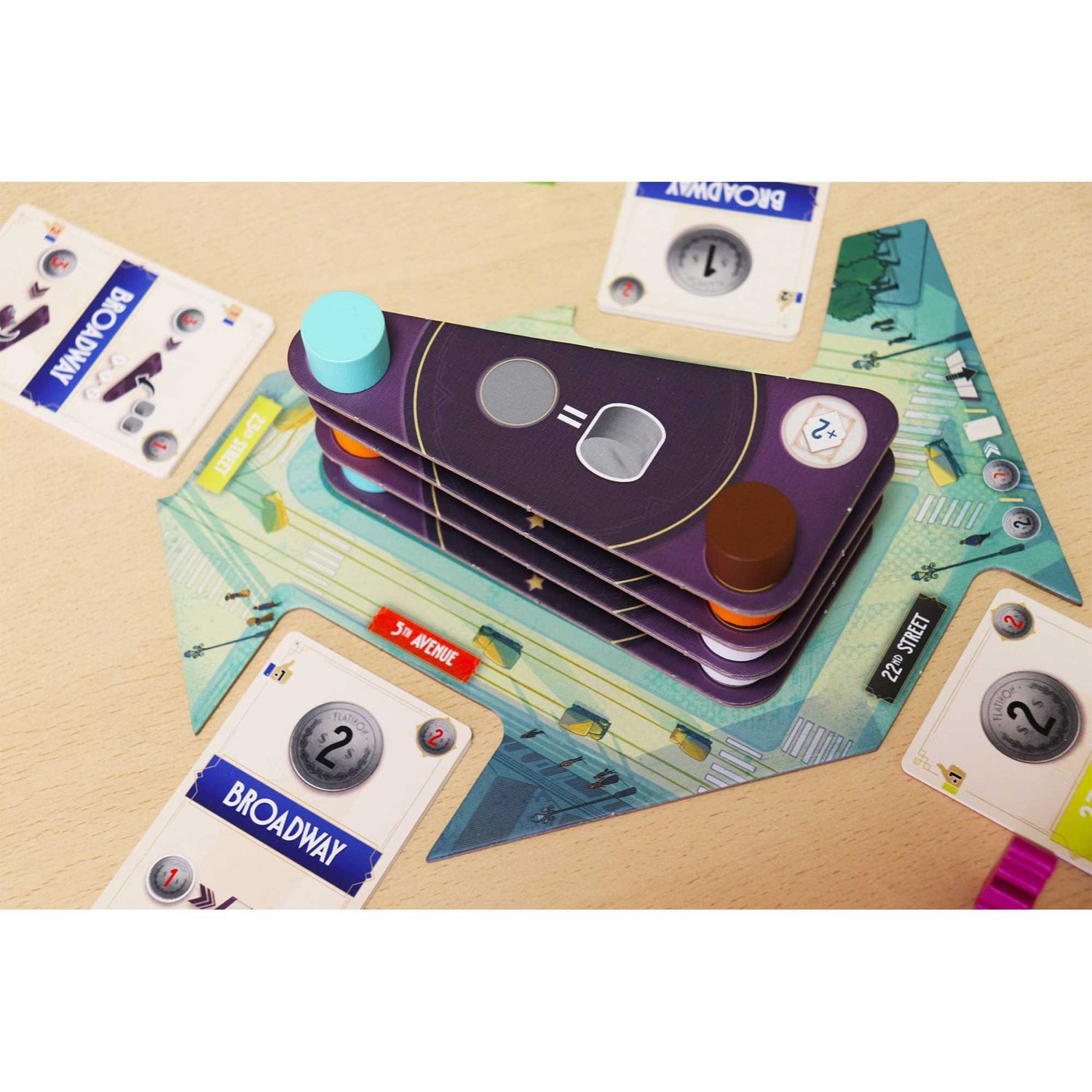 Juego de mesa con cartas, peones y un tablero con señales de calles.
