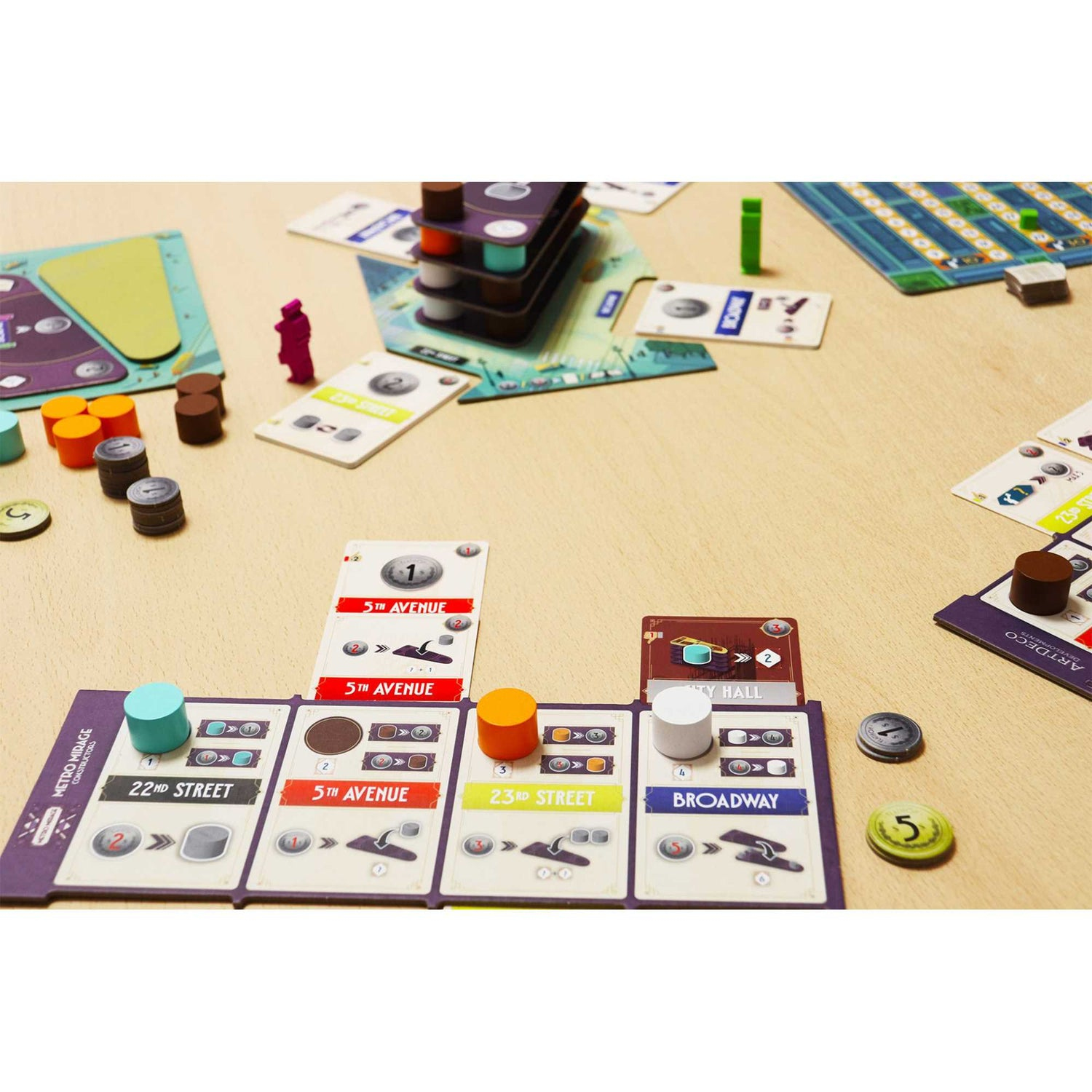 Juego de mesa con cartas de ciudad, cilindros y peones sobre mesa de madera.